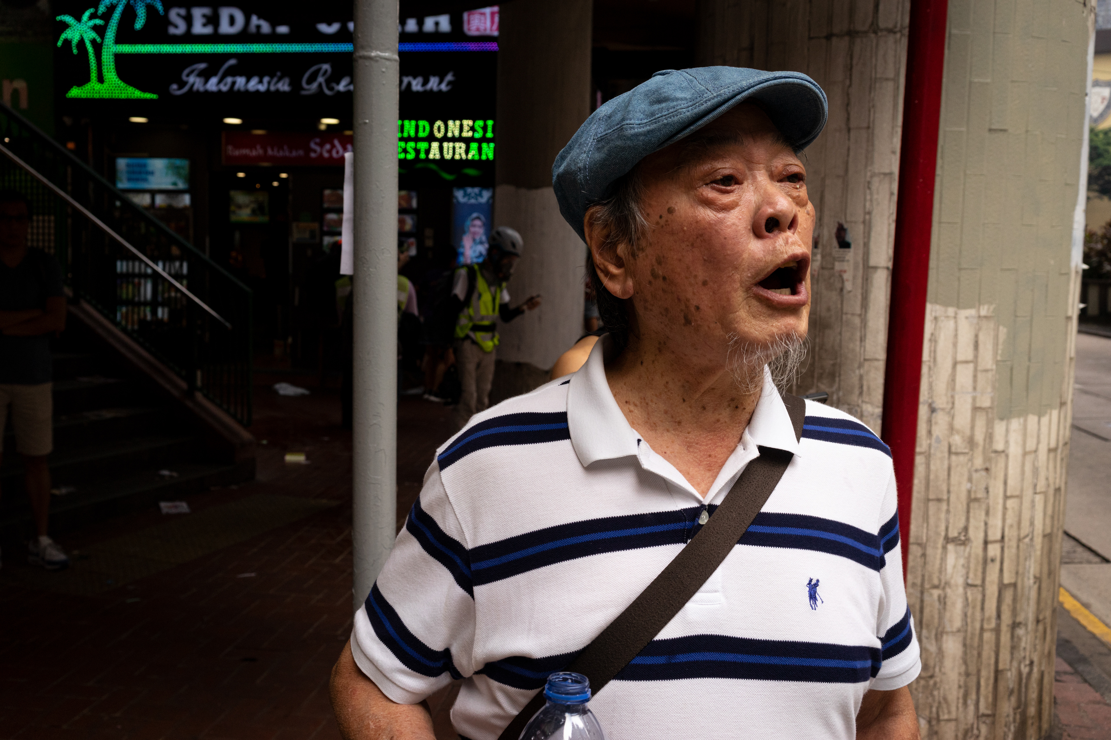 Furious: Causeway Bay, Hong Kong: The sudden deployment of tear gas catches many citizens simply passing by or working in local shops, utterly unprepared and leaves citizens furious. Here, an elderly gentleman shouts profanities at the riot police for their behavior. Following the 5th anniversary of the Umbrella Movement, protesters encounter violence from police on a scale that has not been seen before. September 29, 2019-Hong Kong