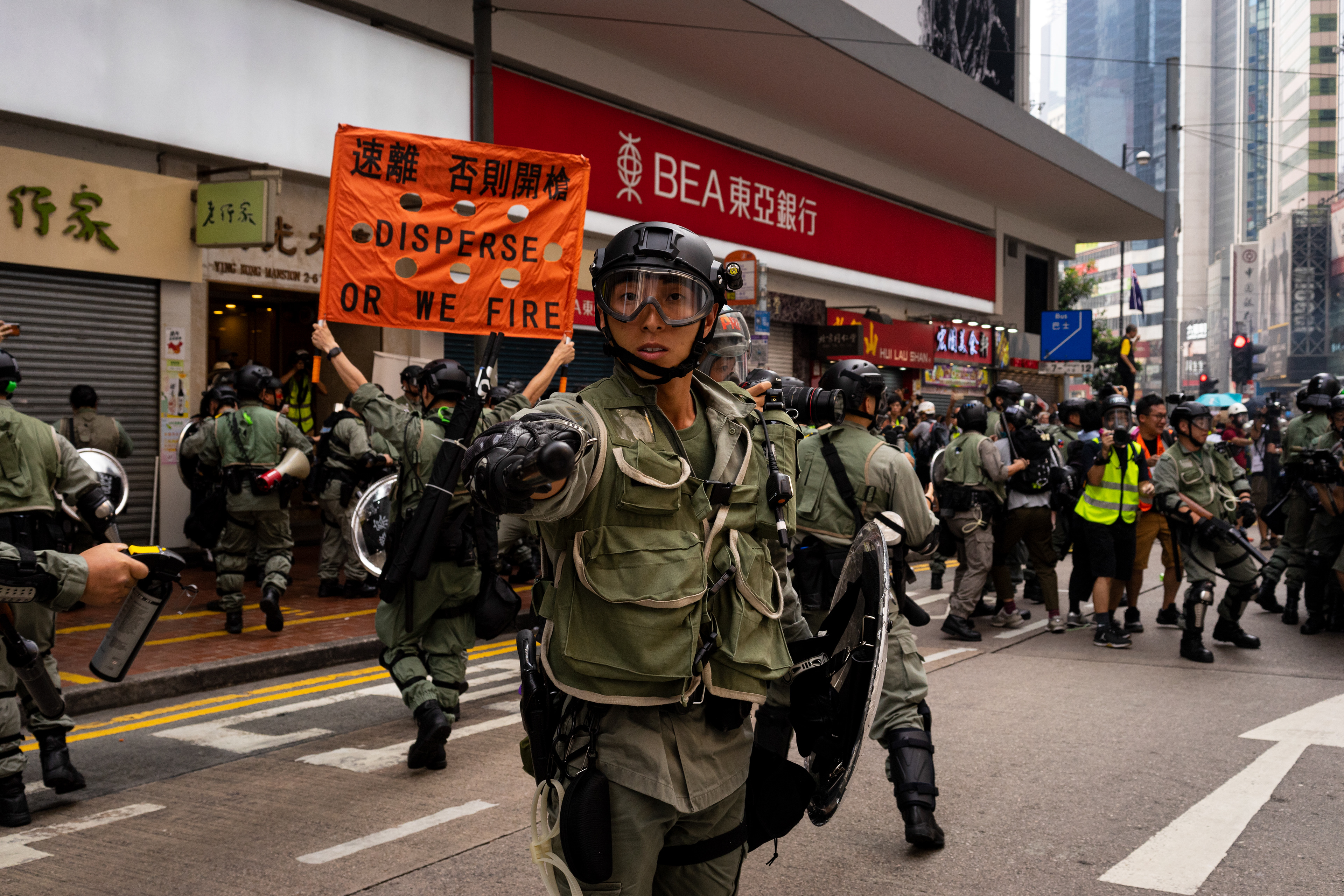 Disperse: Causeway Bay, Hong Kong: Riot police, after dousing a crowd of journalists with pepper spray, move immedietly to tear gas. It takes them no time at all to saturate the entire intersection. Following the 5th anniversary of the Umbrella Movement protestrors encounter violence from police on a scale that has not been seen before. September 29, 2019-Hong Kong