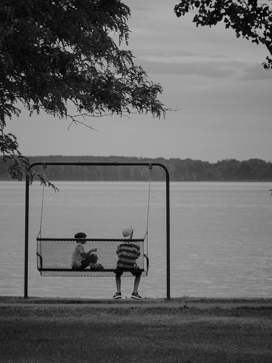 Montréal, 2018. Two boys look towards the Saint-Laurence River as they sit on a swing.