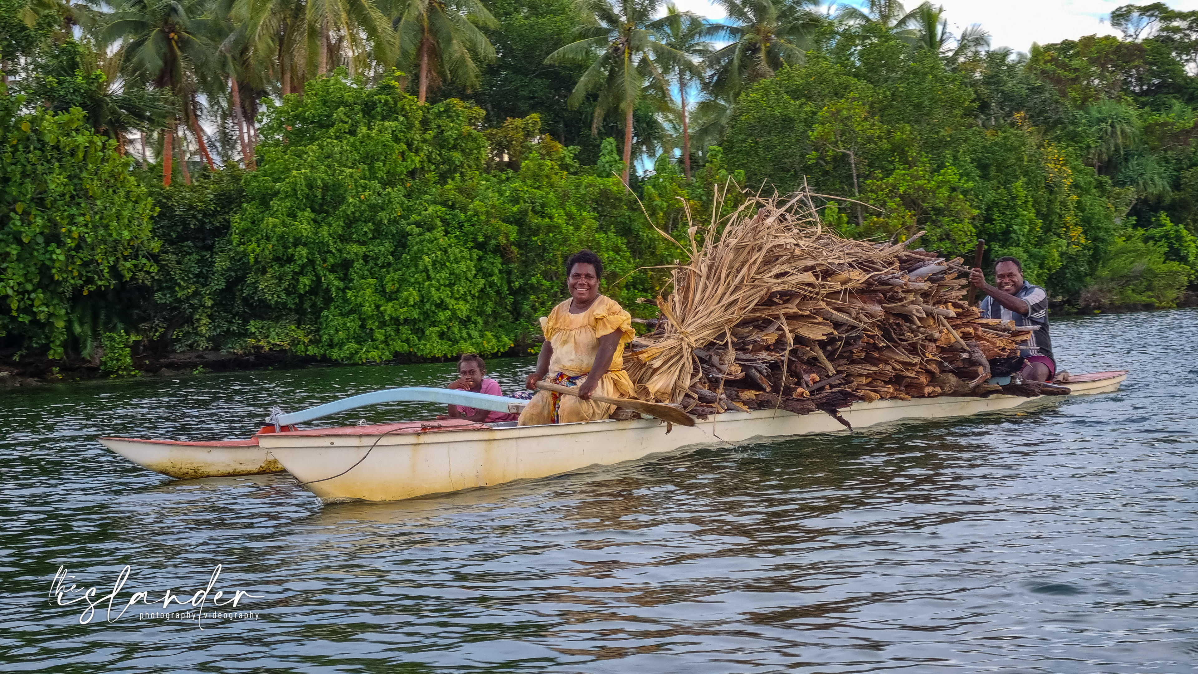 Happy smiling family paddling back to the village with their firewood 