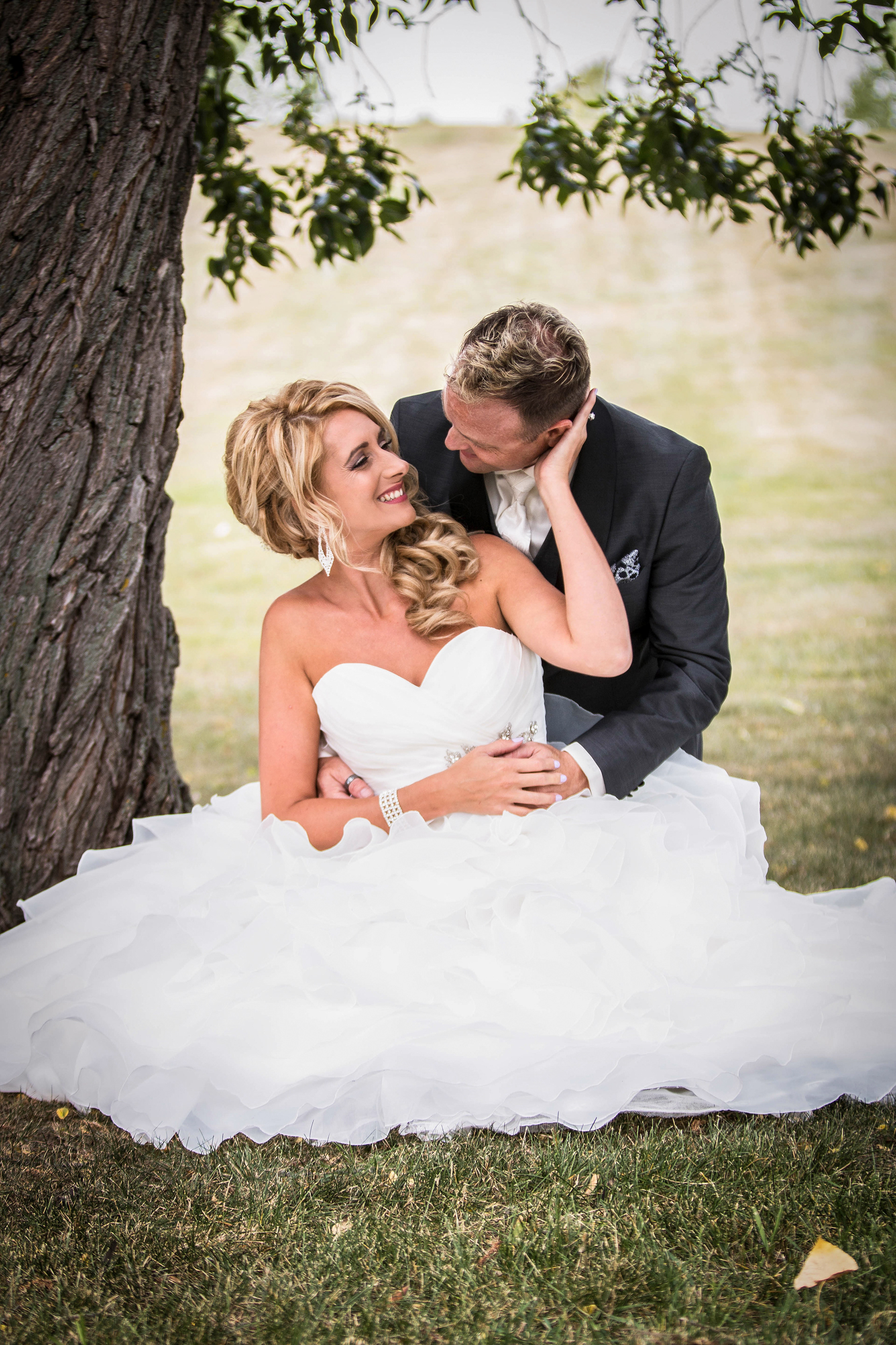 Bride and groom sitting by a tree in Edmonton Alberta