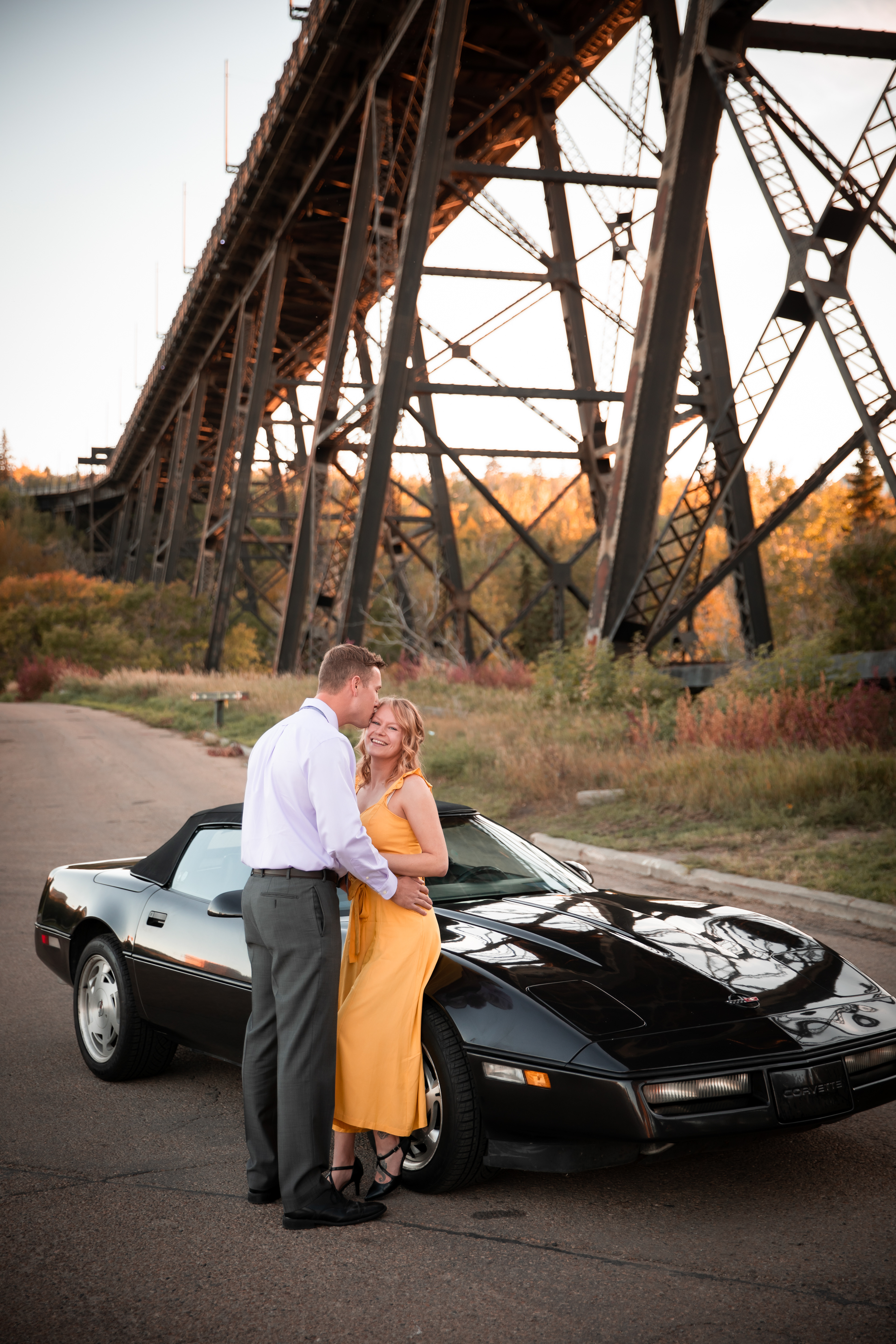 couple kissing standing beside their car