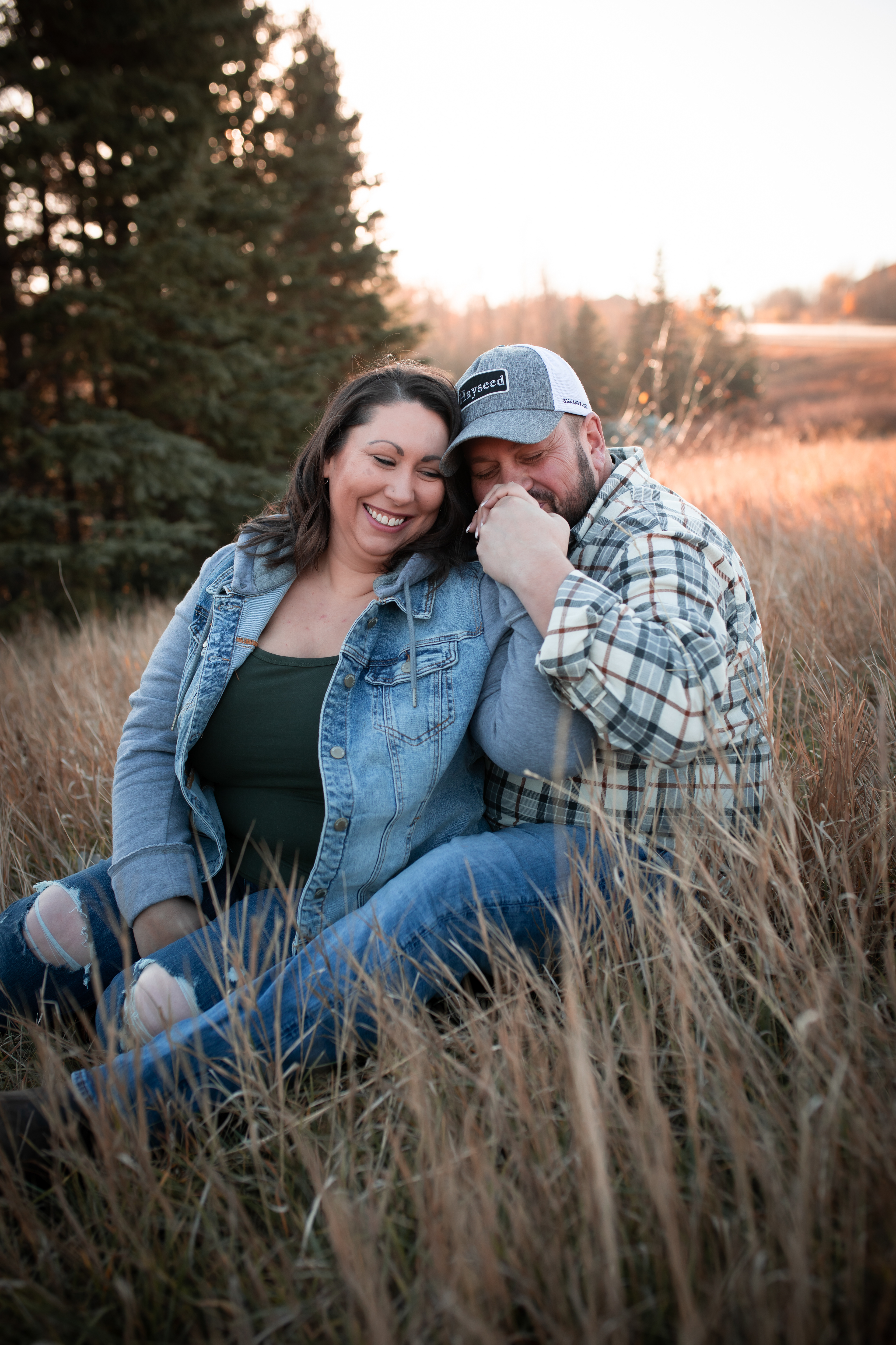 couple sitting in tall grass Edmontons best engagement photographer