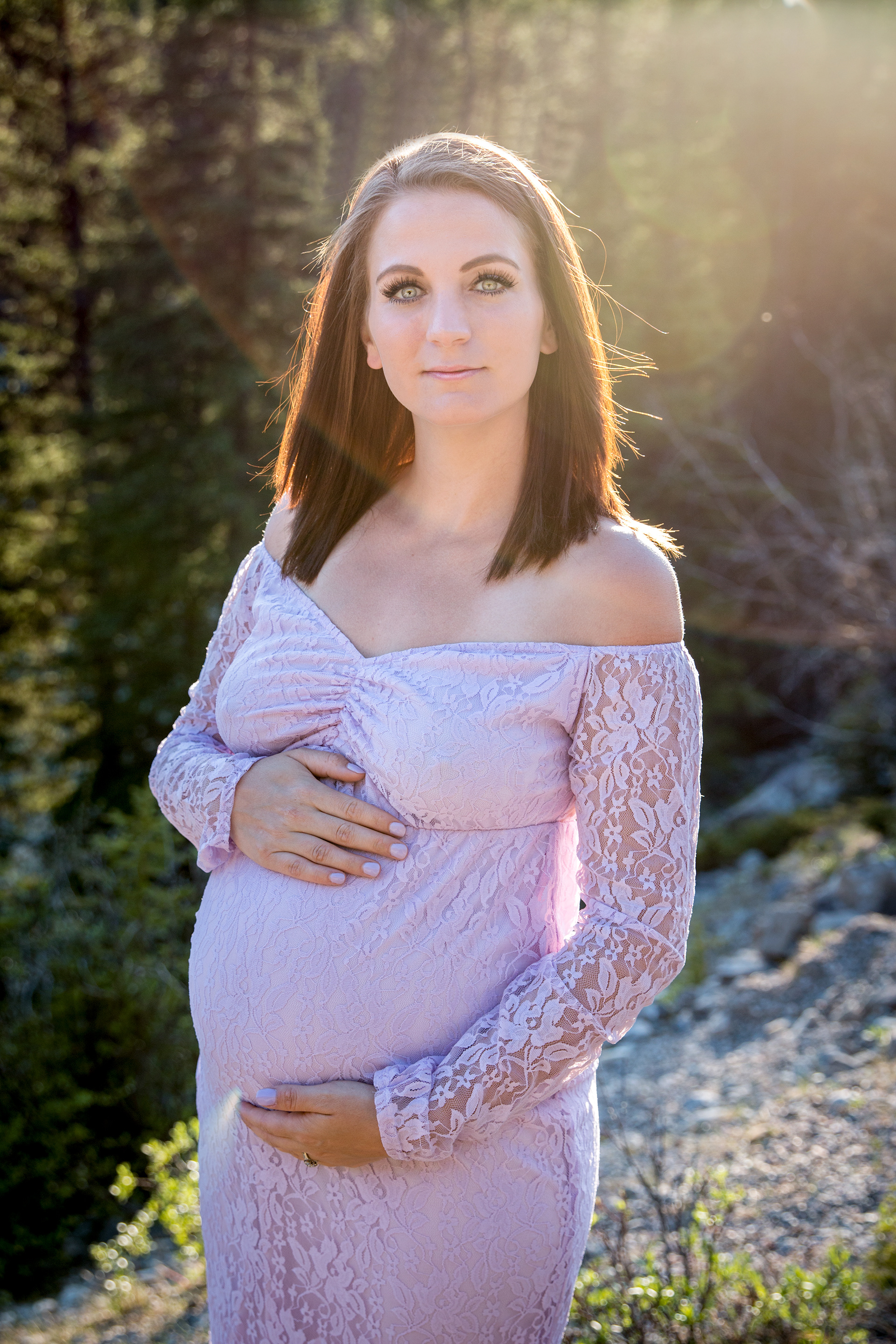 Mom holding belly in mountains in the sunshine