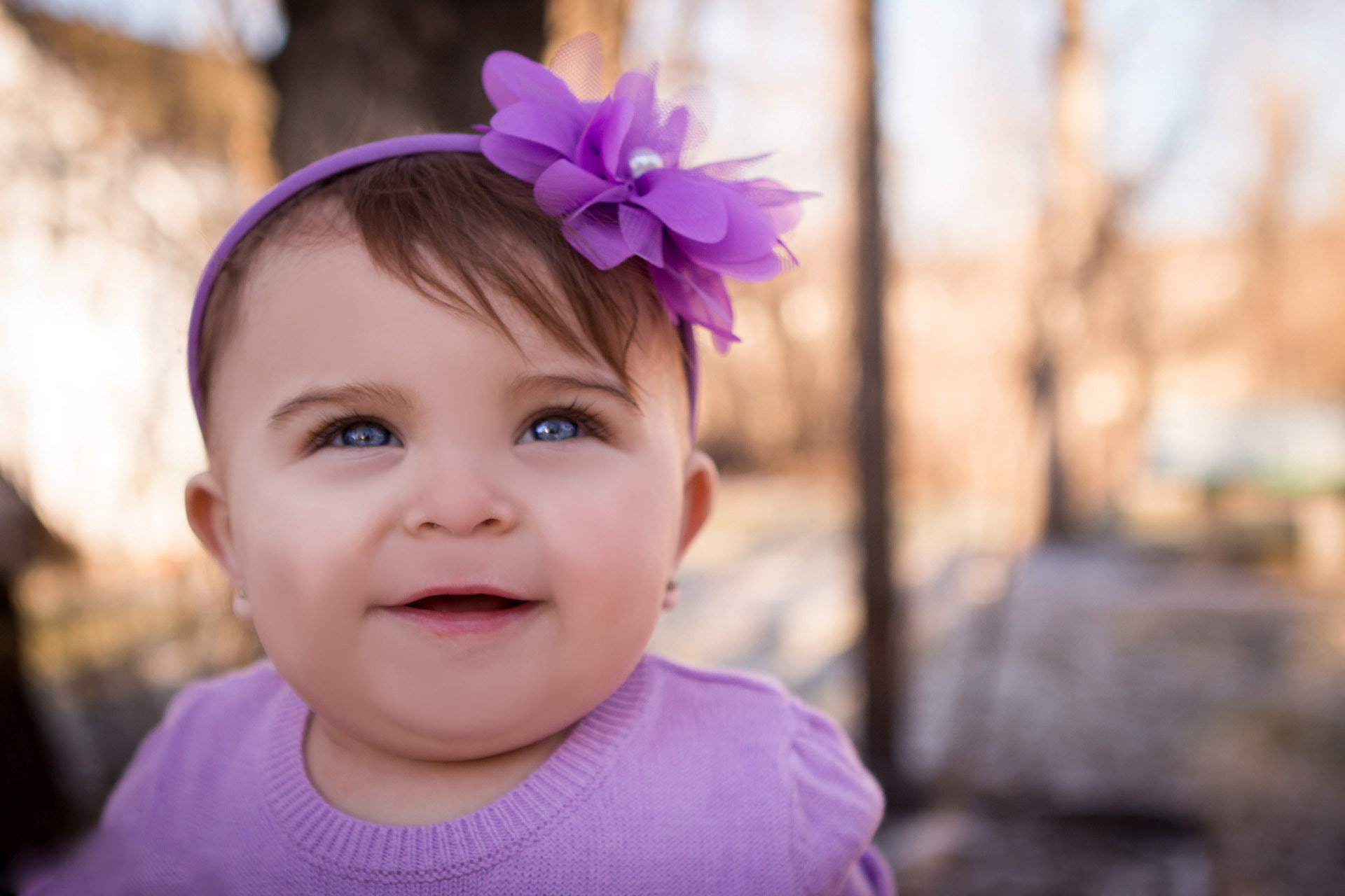 baby smiling in purple with big blue eyes