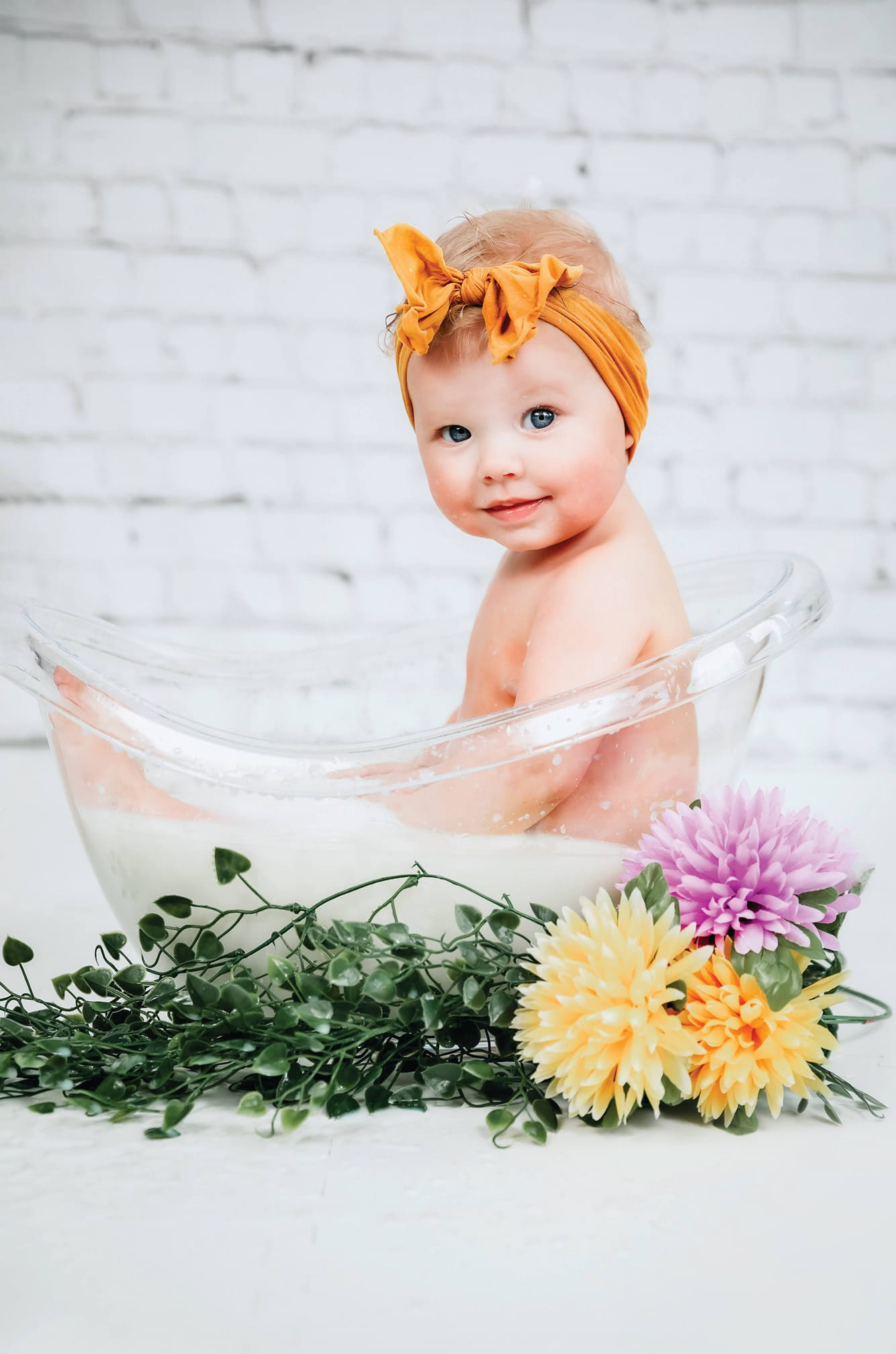 baby in milk bath smiling 