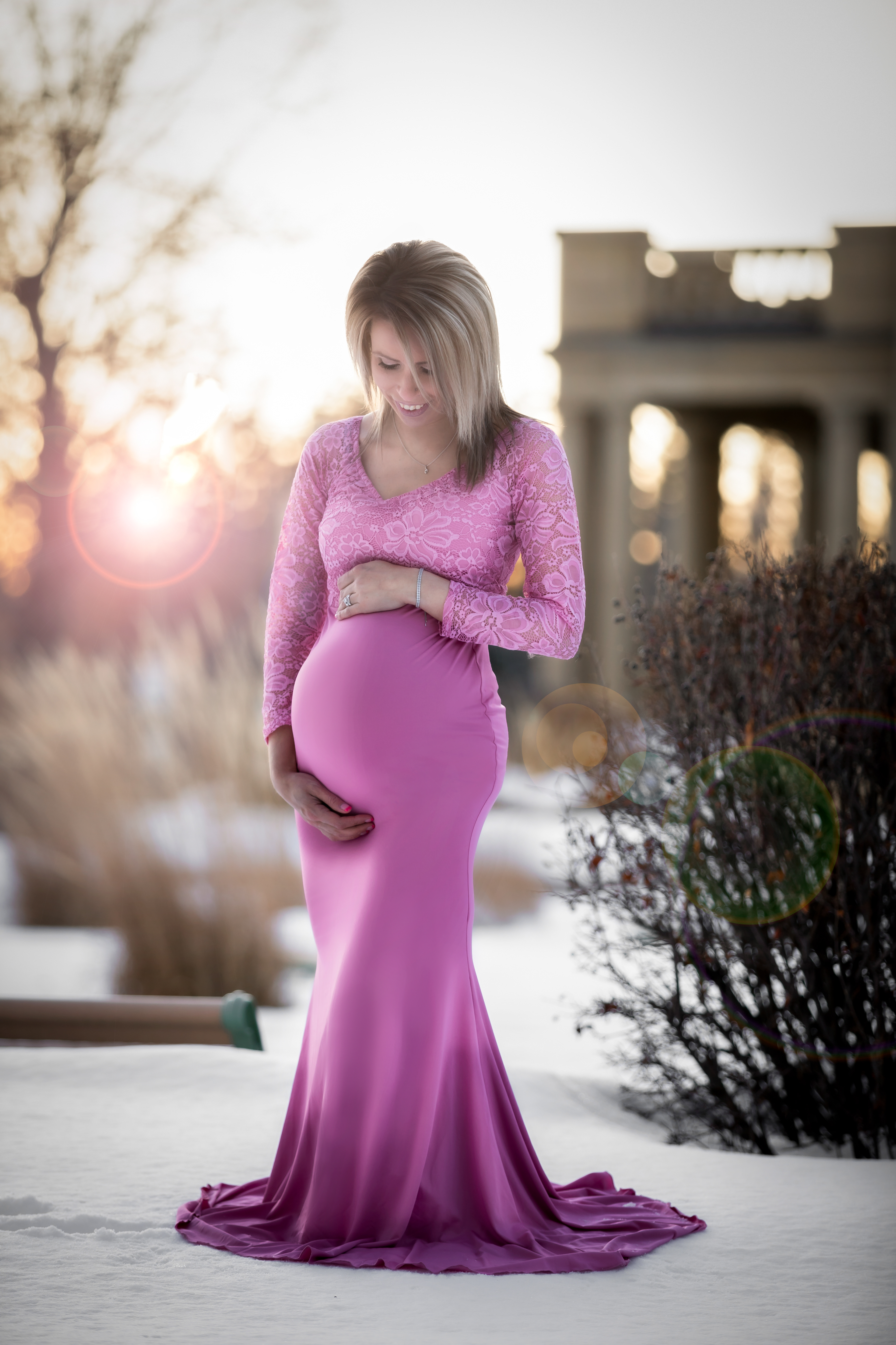 mom holding belly smiling in a pink dress