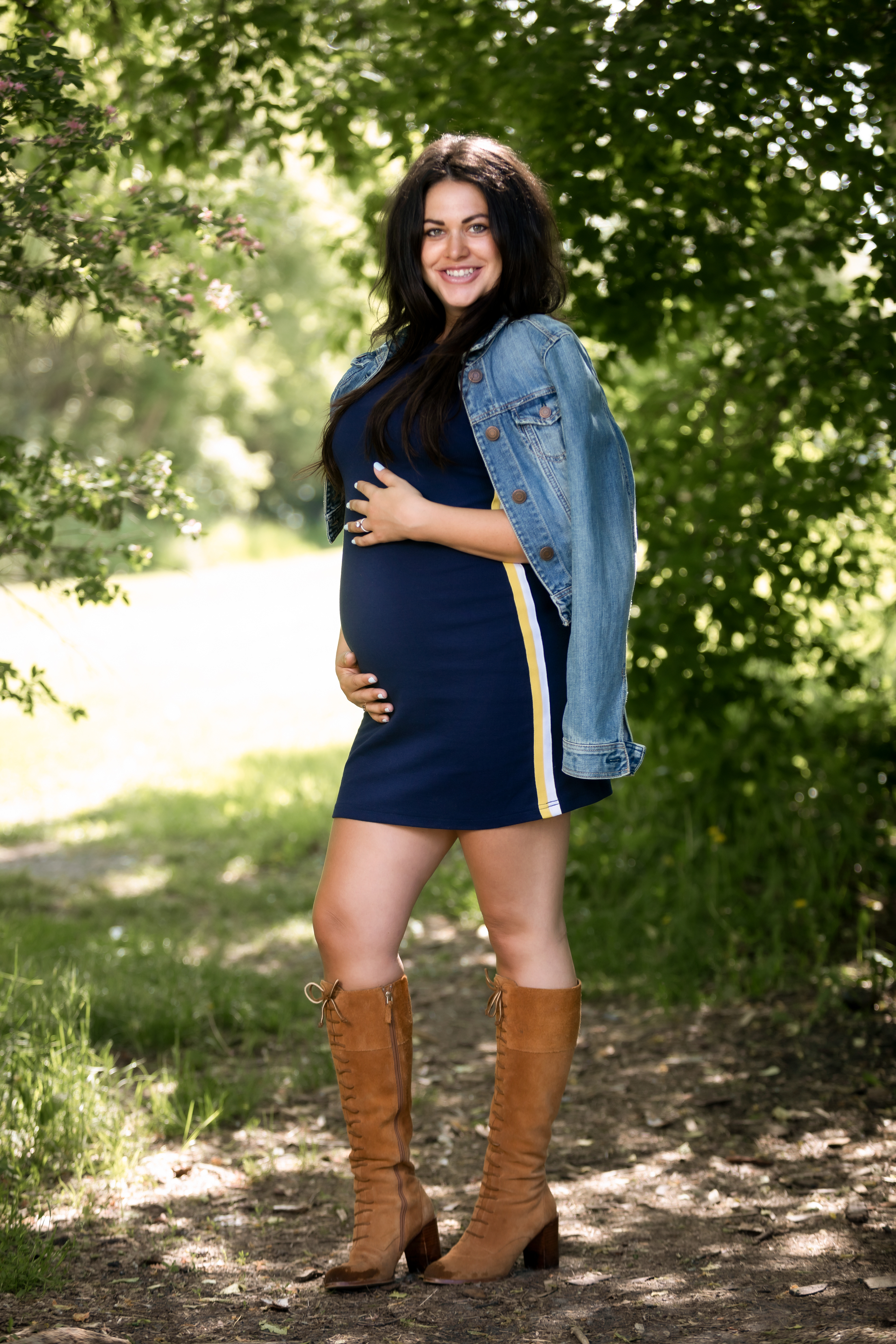 mom holding belly smiling wearing a jean jacket
