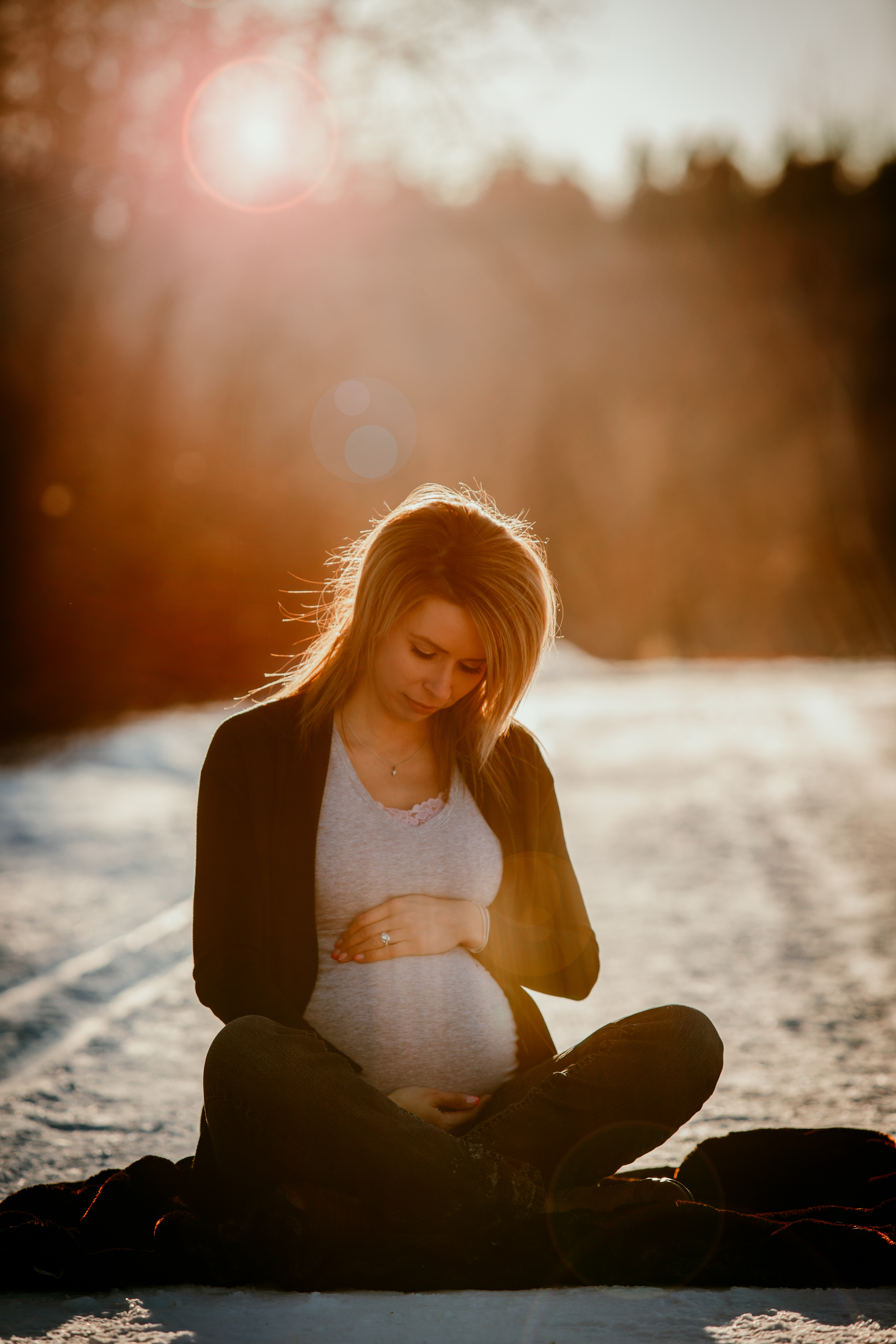 mom holding belly smiling sitting in snow