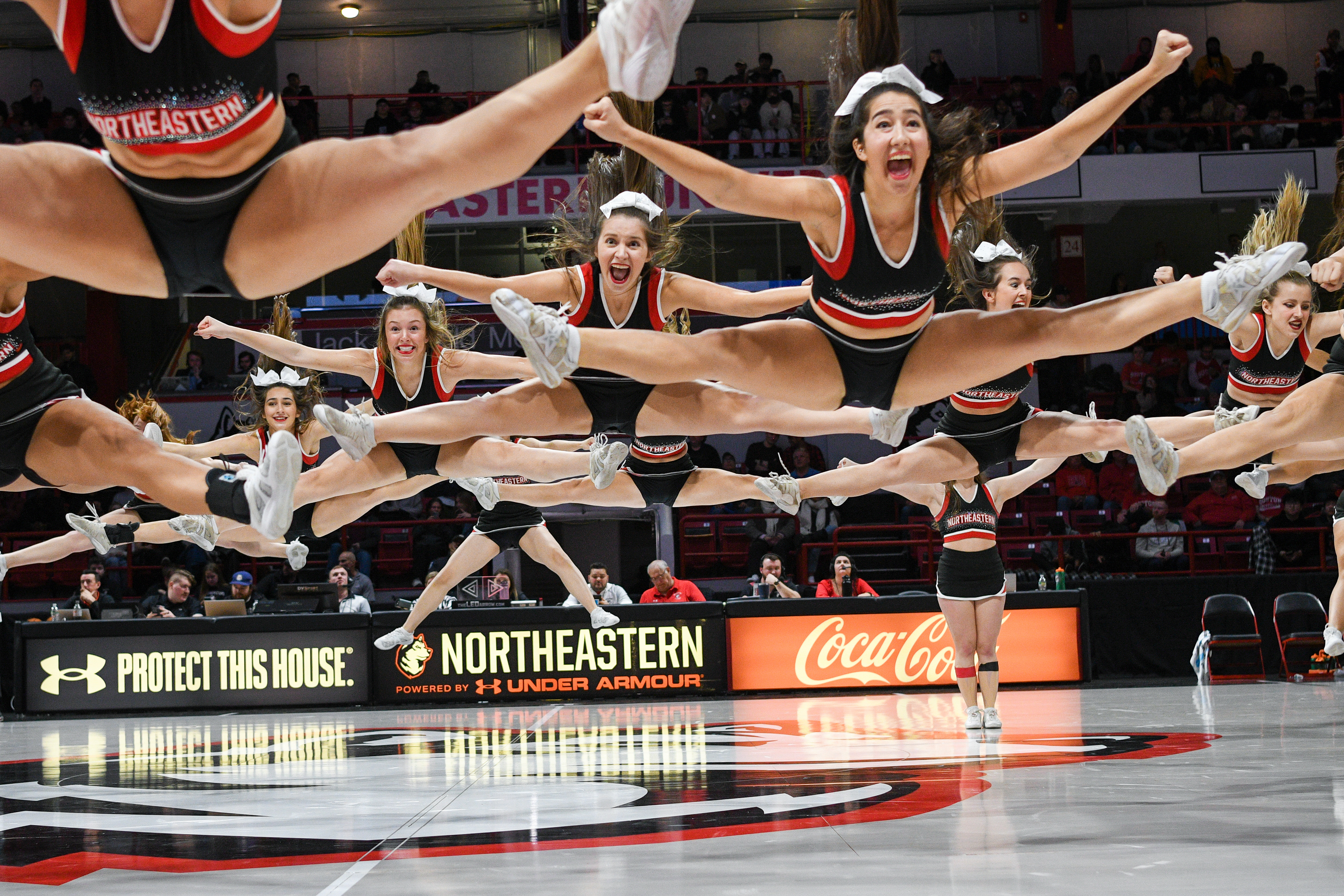 Northeastern Cheer 2023 : Team performing a straddle jump during media break at a basketball game