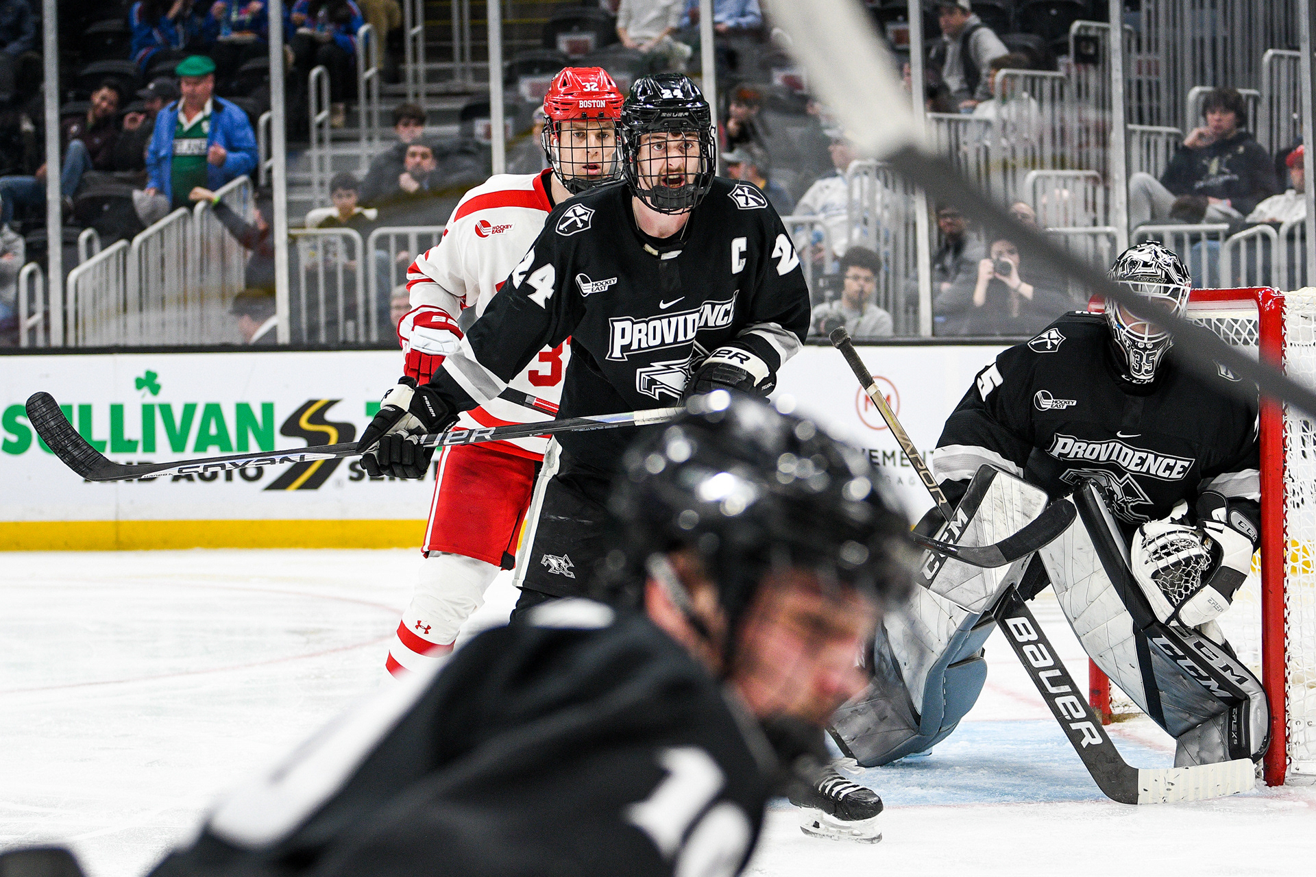 Providence College defenseman Max Crozier blocking Boston University forward Wilmer Skoog from getting near the puck.