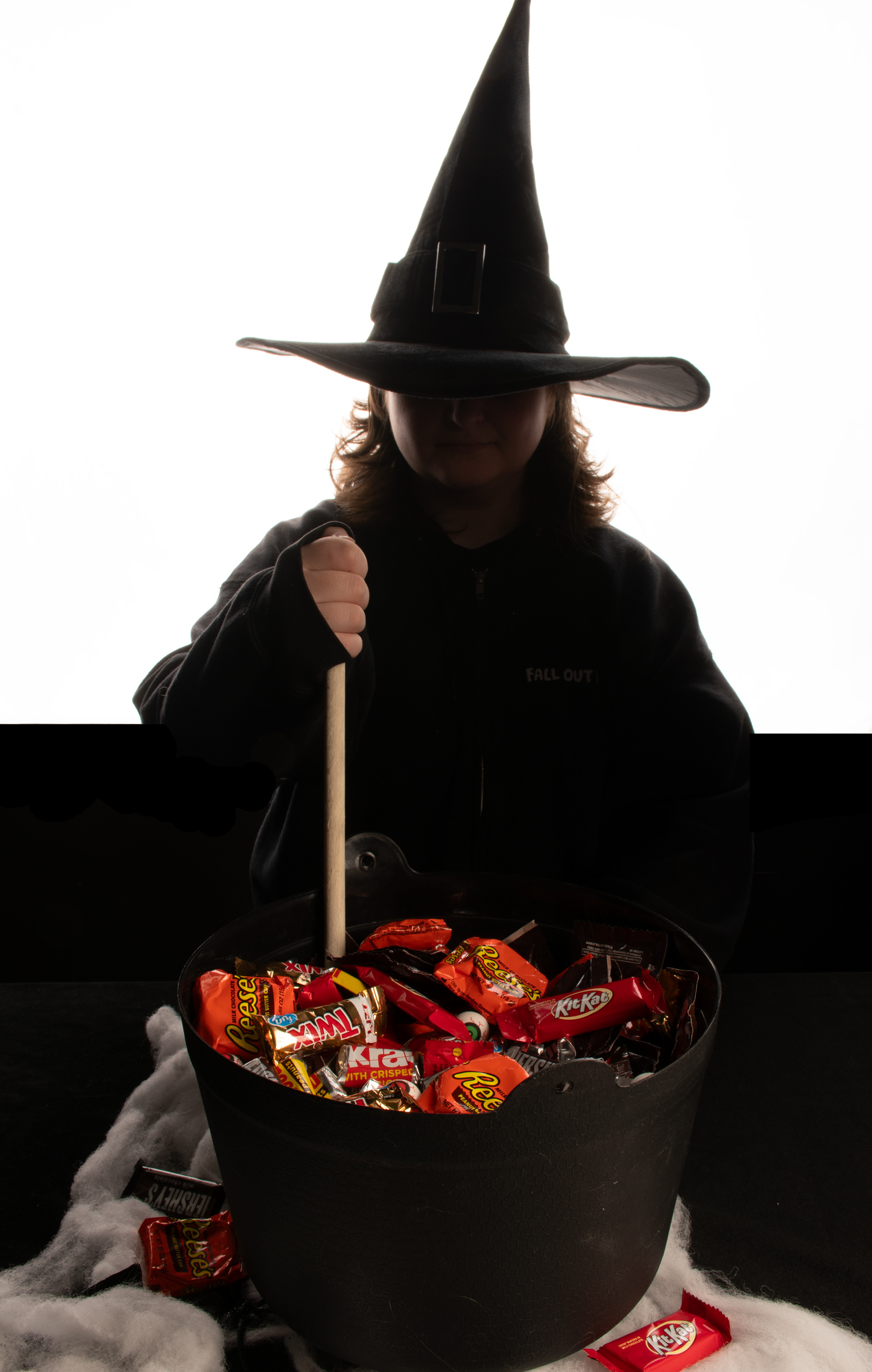 Witch studio shot of model "stirring" a pot of halloween chocolates. Model: Marissa G.