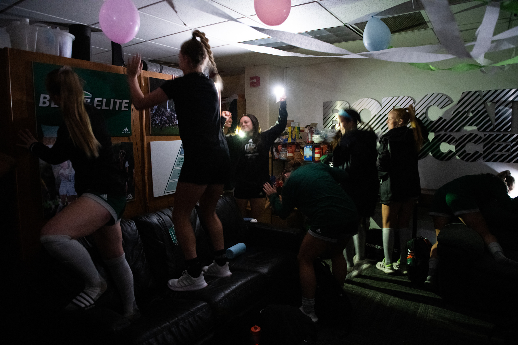 Players of the Ohio Women’s Soccer Team shine their phone flashlights and bang on the wall during their pregame ritual in Athens, Ohio, on Sunday, Oct. 23, 2022.