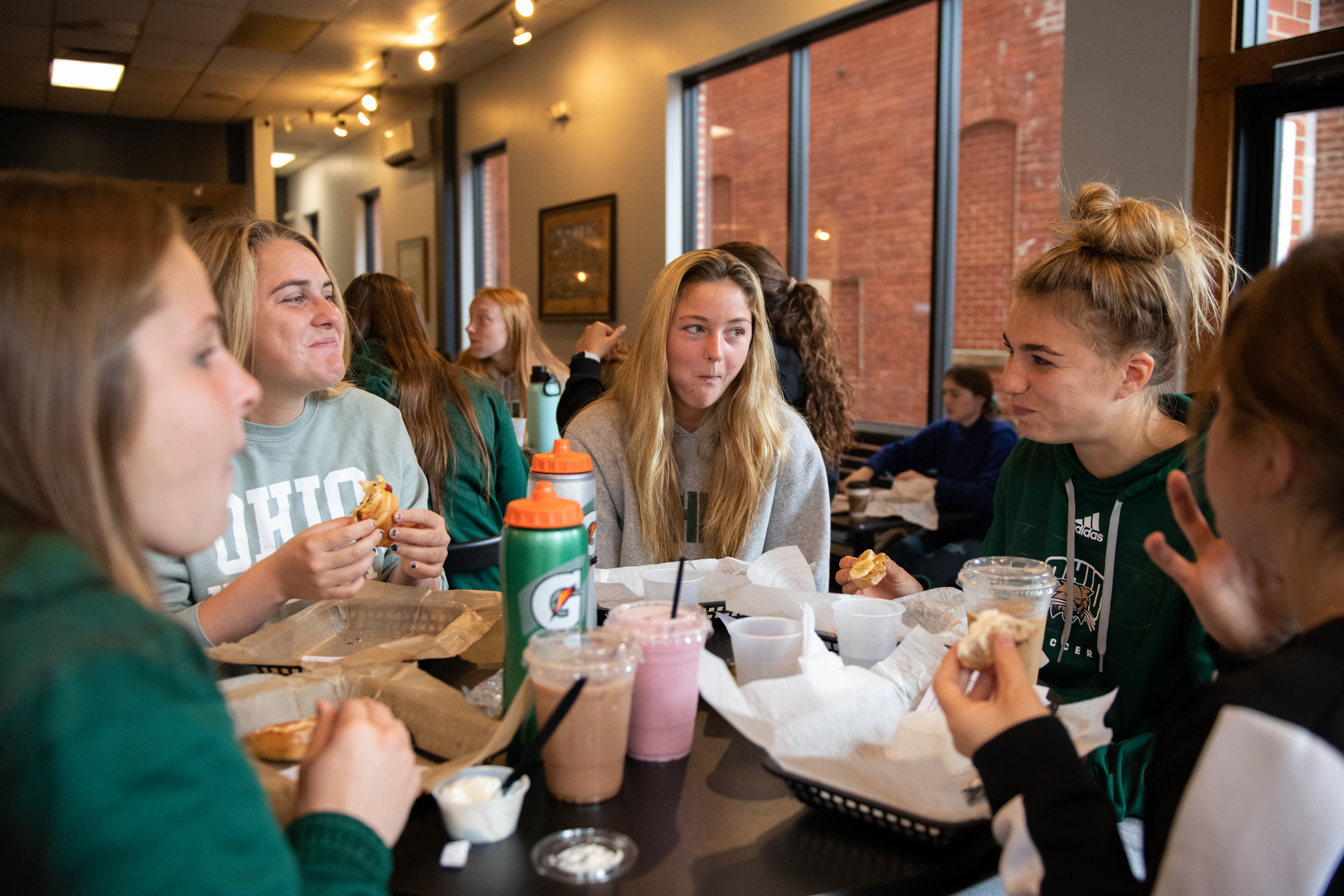 Celeste Sloma (left), Kali Stock (center) and Quintin Tostevin (right) laugh during breakfast before their game against Ball State in Athens, Ohio, on Sunday, Oct. 16, 2022. The team meets at Brenen’s Coffee Café for breakfast before each home game.