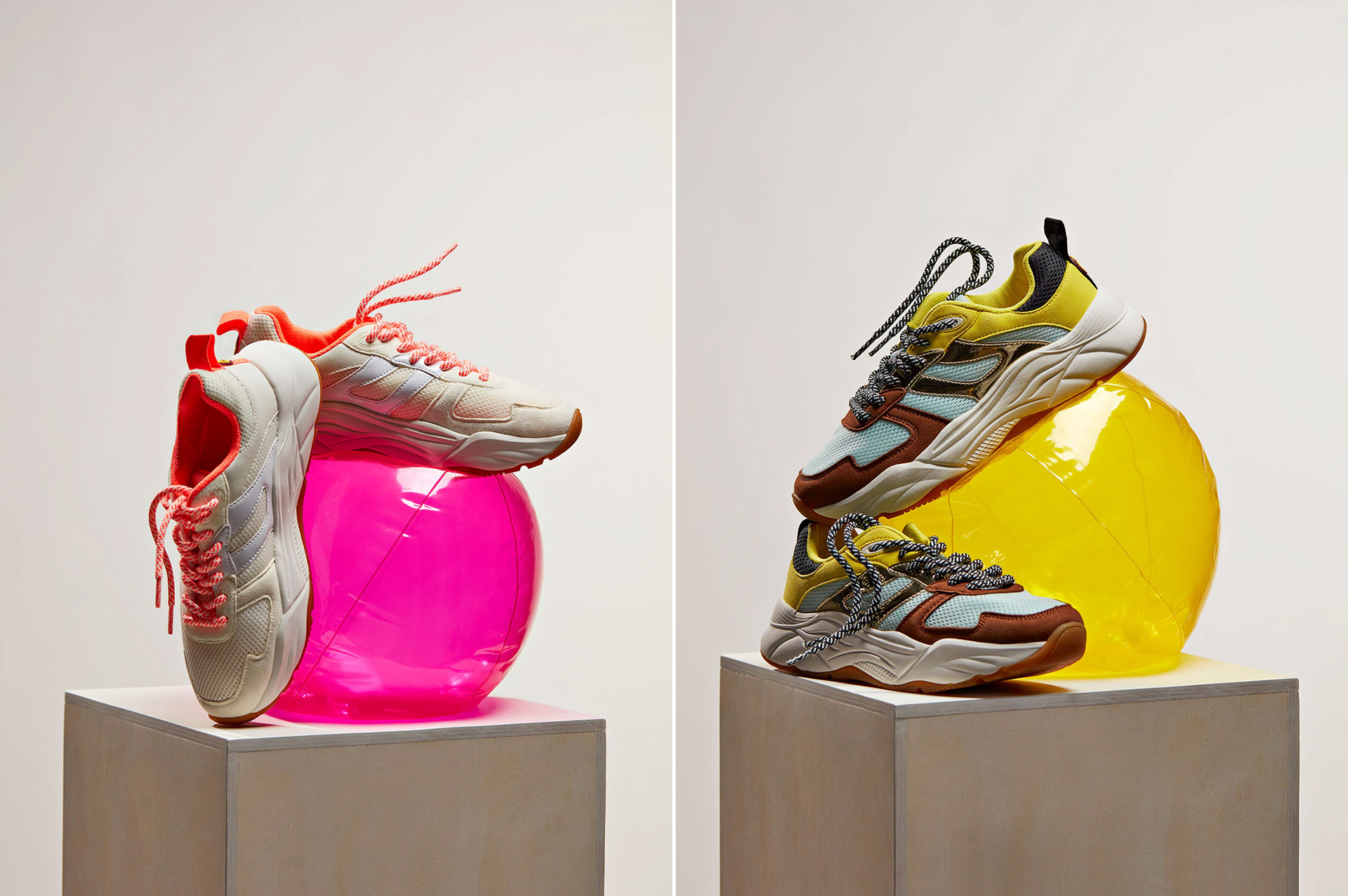 Still life images of shoes with funny laces styled in a nice way are displayed on brightly coloured beach balls that are not completely full of air.