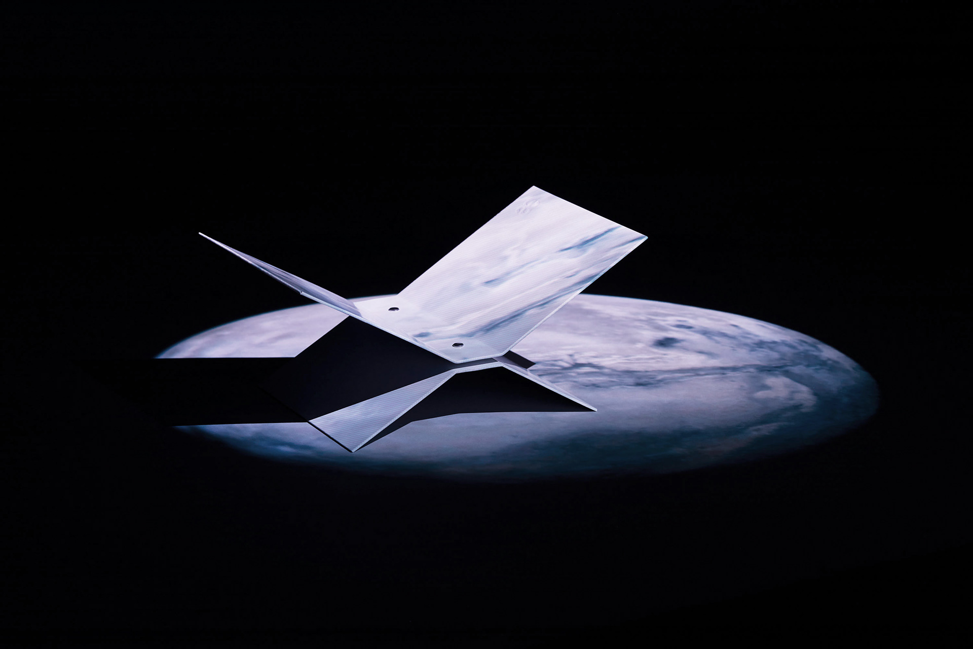 In a dark studio, a beamer projects the image of earth onto a white bookstand design object