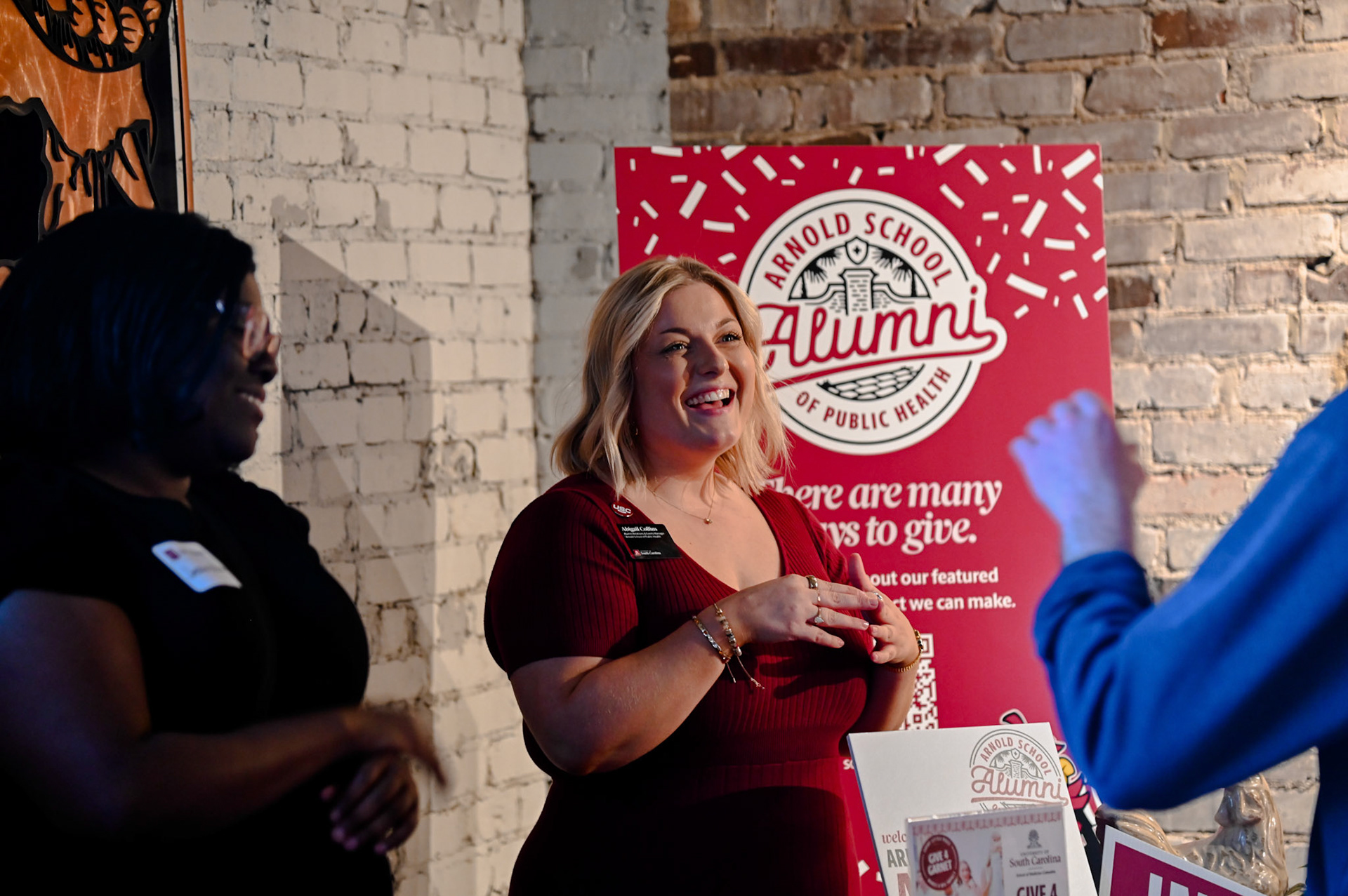 Abigail Collins speaking in front of a sign with "Arnold School Alumni: There are many ways to give."