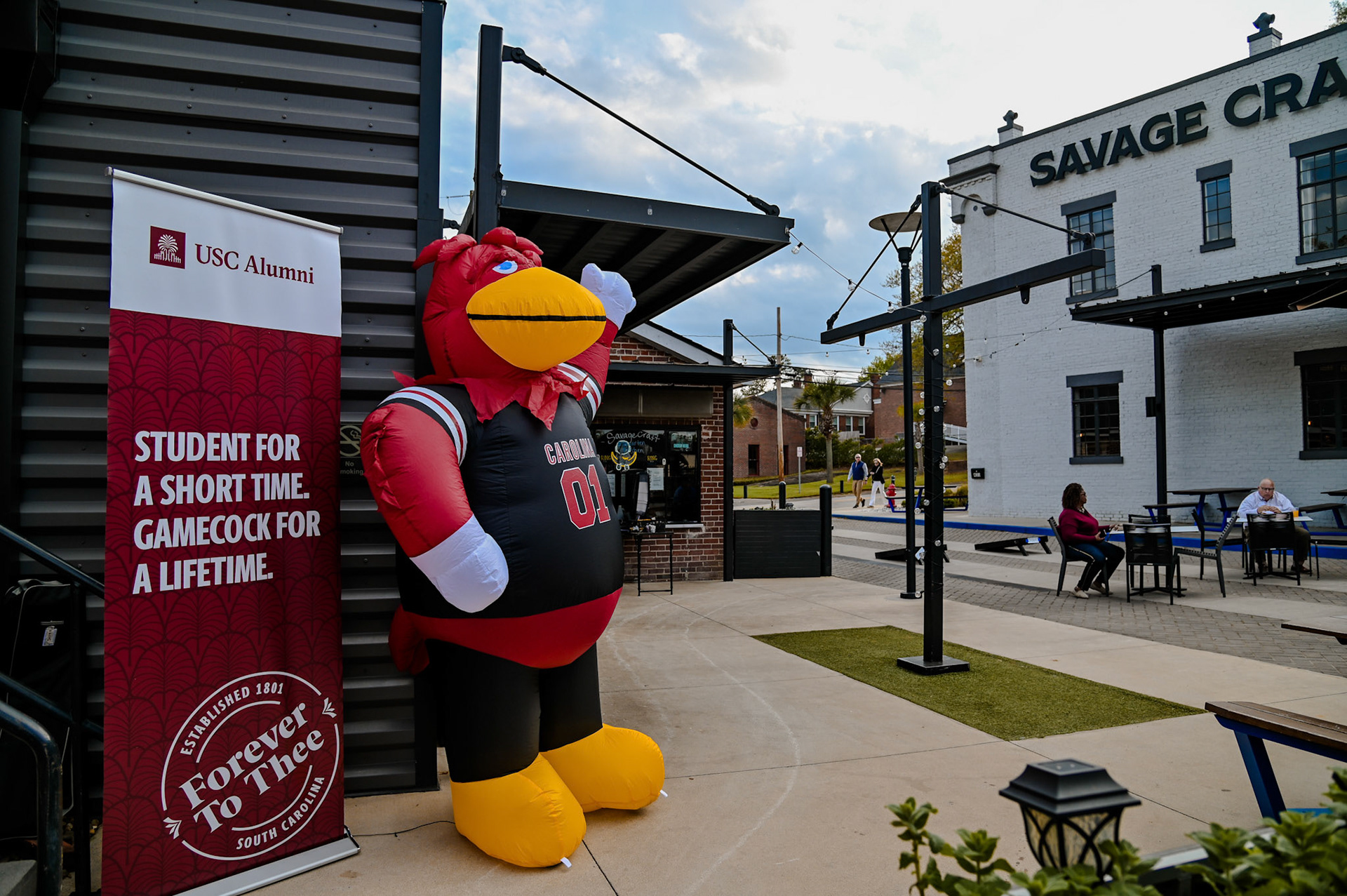 Inflatable Cocky mascot standing next to a banner that says, "students for a short time. Gamecock for a lifetime."