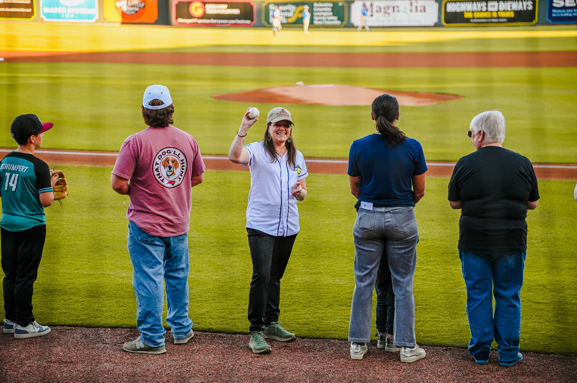 Dean Sabo-Attwood waiting to throw the first pitch at the baseball game and holding up a baseball for the crowd