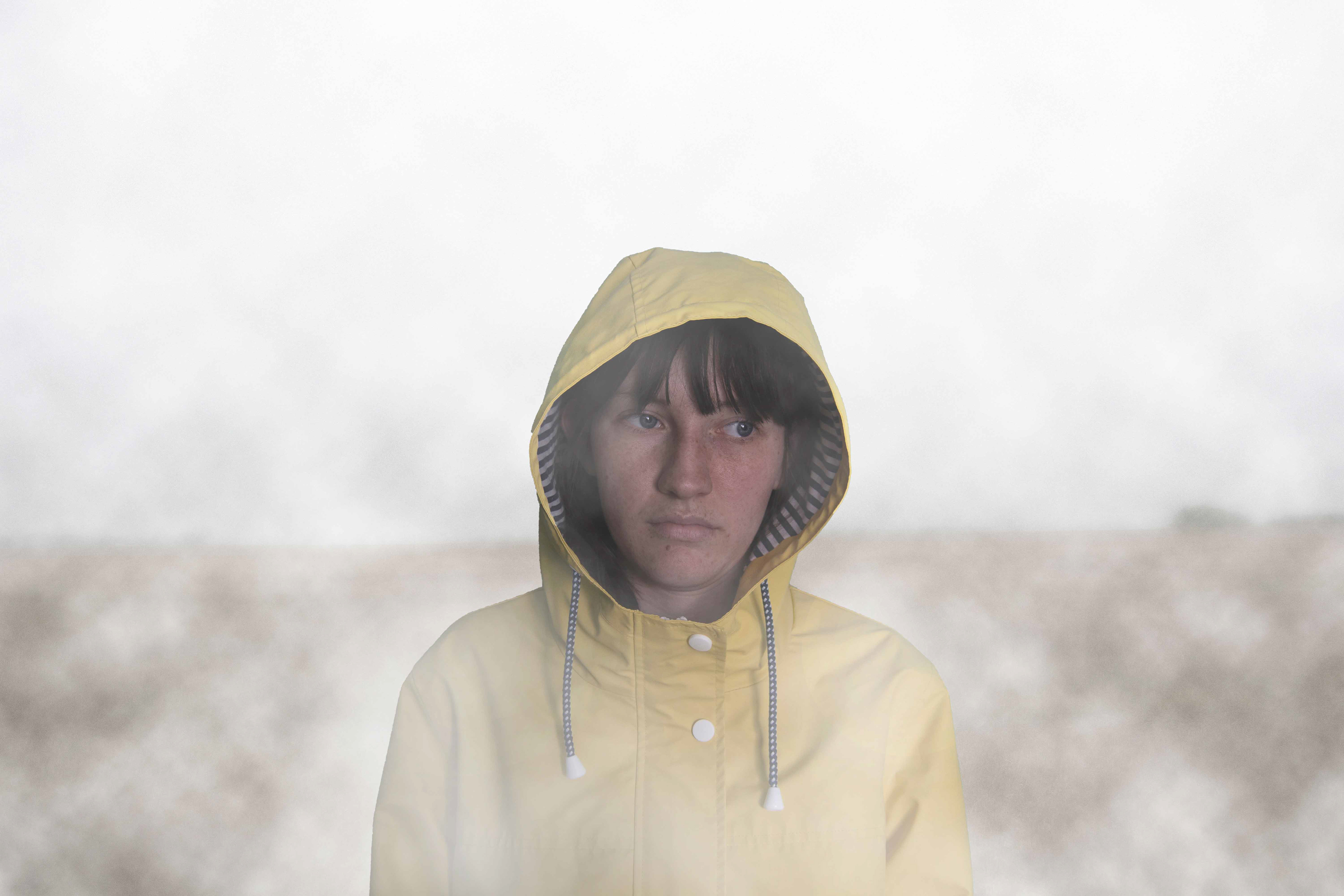A woman in a yellow coat, alone.