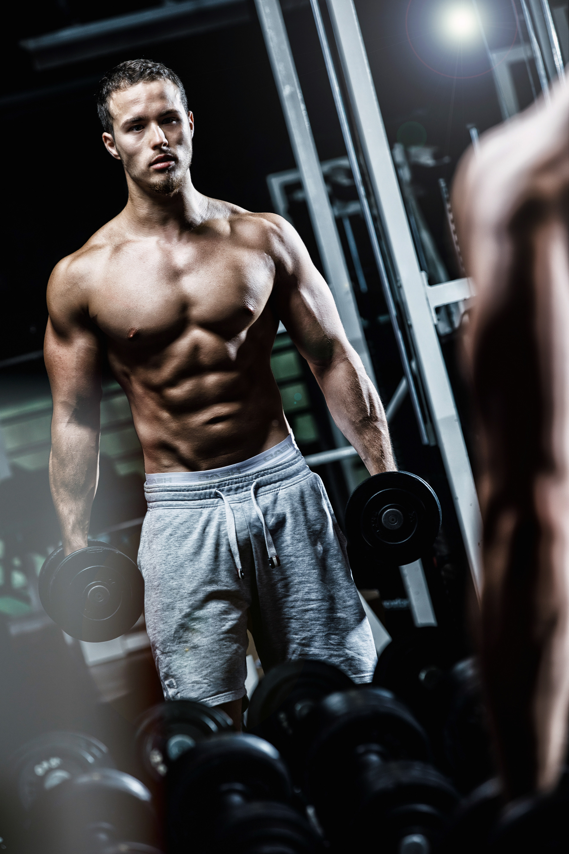 Bodybuilder mit Kurzhanteln vor Spiegel