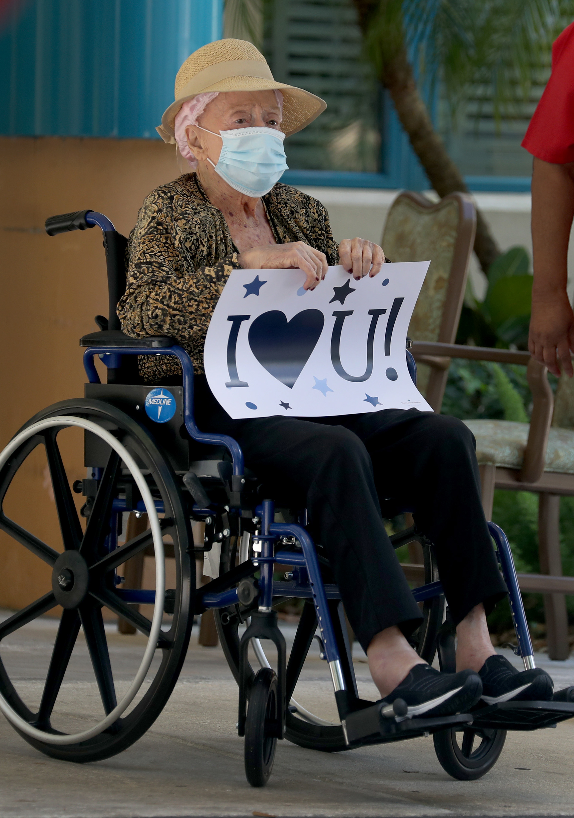 A resident of a Miami assisted-living facility sends a message to her family as they do a drive-by visit during the COVID-19 pandemic in 2020.