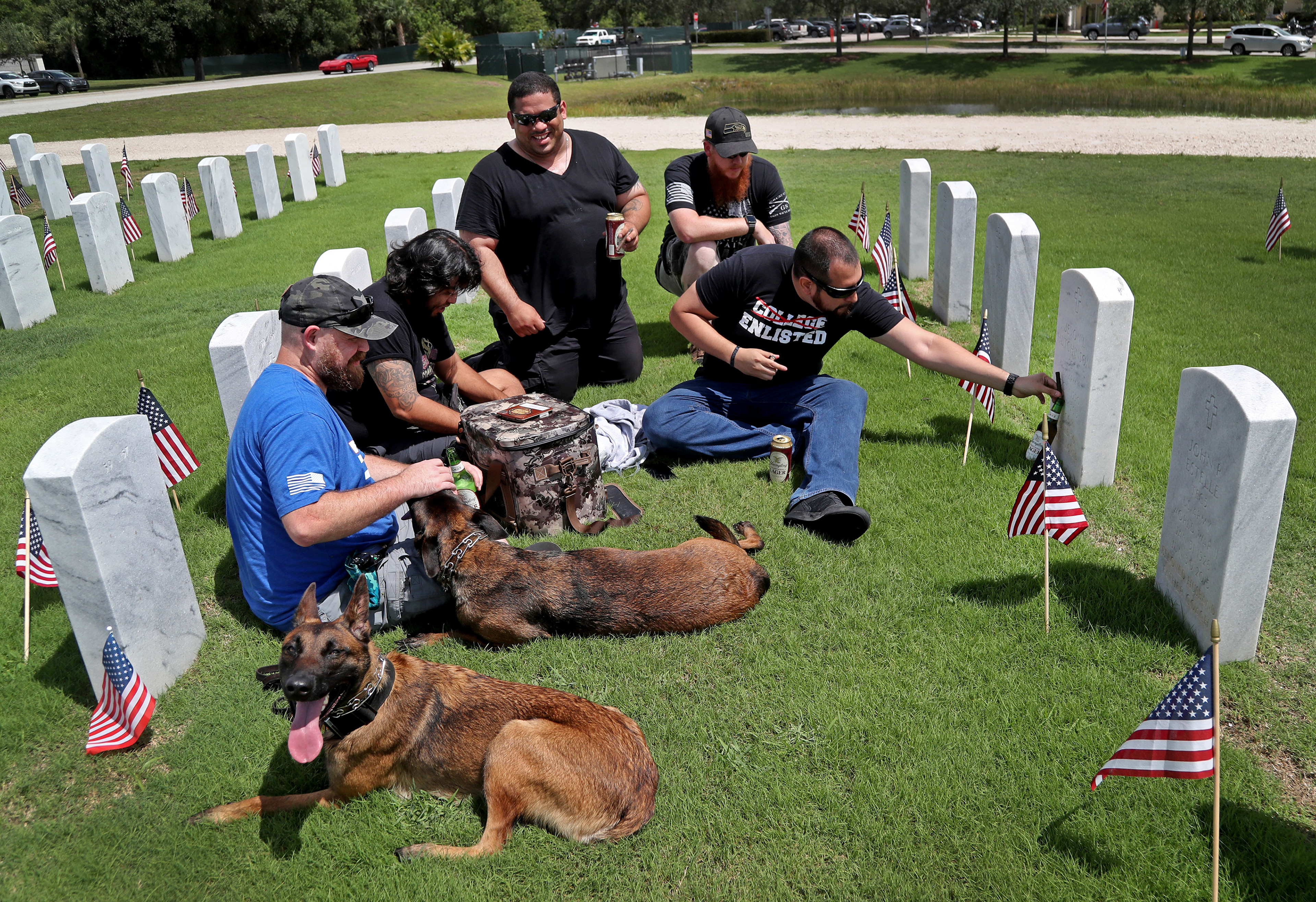 Army veterans who served in Afghanistan and their service dogs visit the grave of a fellow serviceman at the South Florida National Cemetery in Lake Worth, Fl. on Memorial Day 2022.