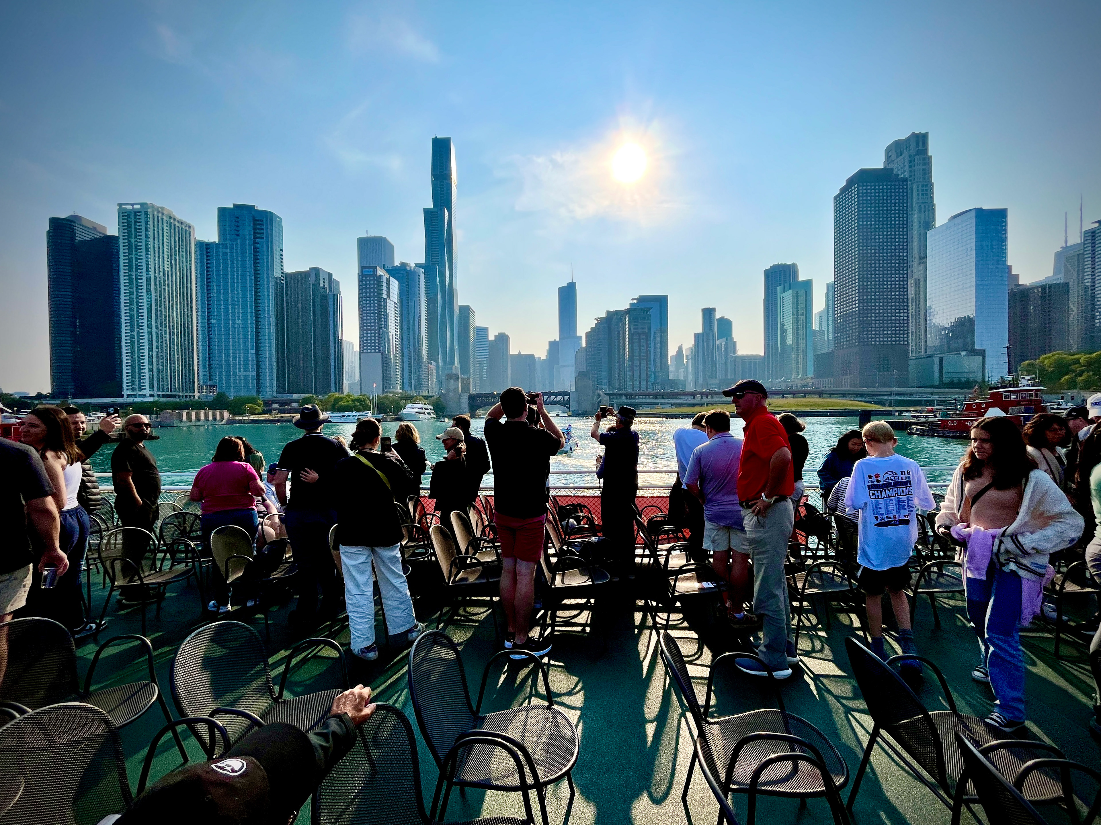 Tourists take photos of downtown Chicago while on an architectural river cruise to learn about the legendary figures who designed and built the city.