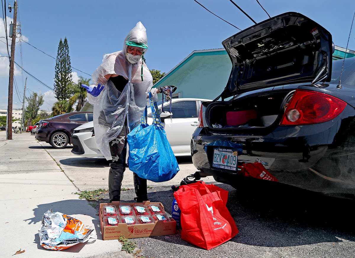 A woman picks up free food from a Feeding South Florida distribution site in Hallandale Beach, Fl. during the early days of the pandemic in 2020..  "I made my own hazmat suit," she said.