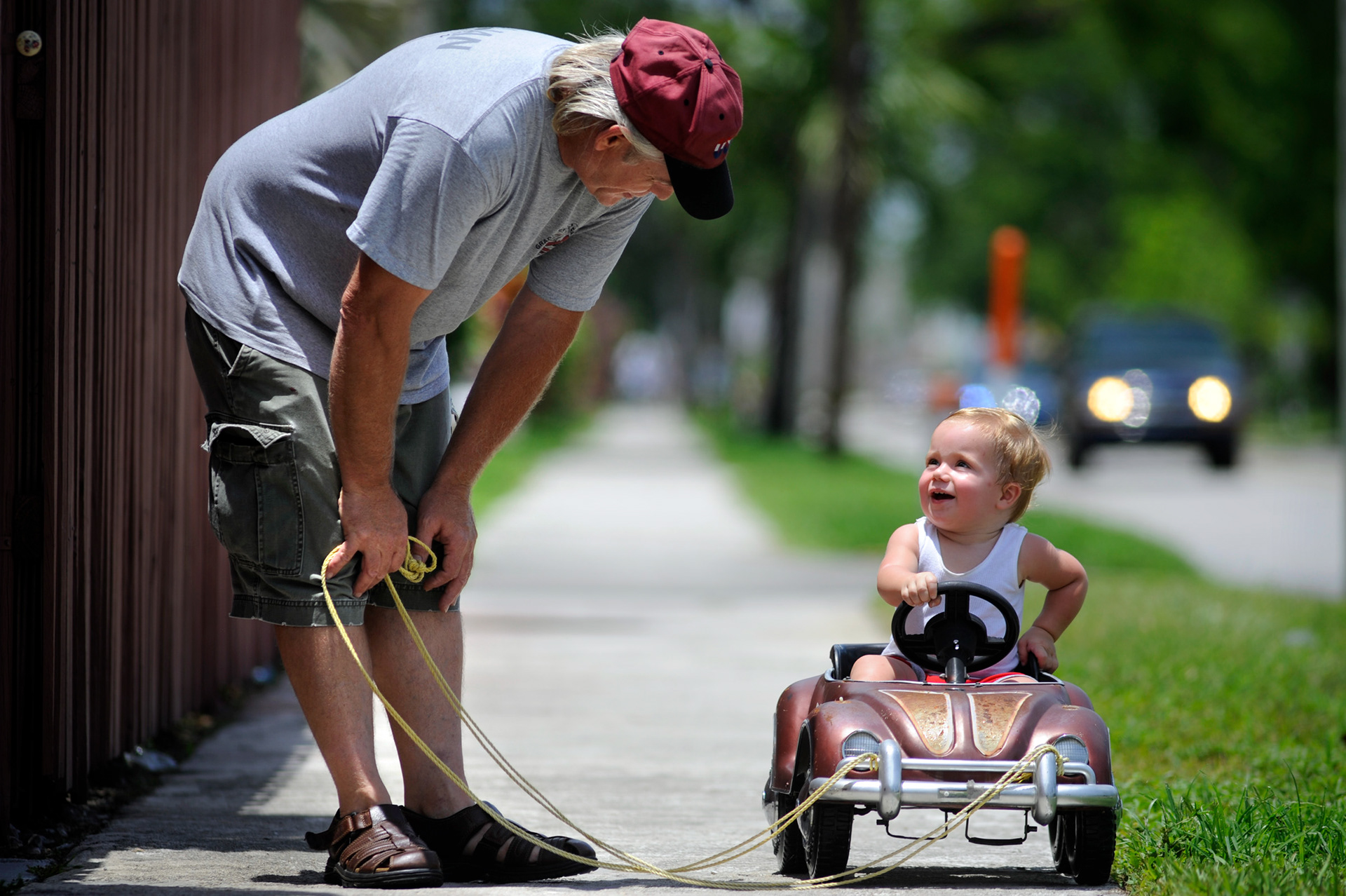 Randy Lynn shares a laugh with his grandson, Caden Parker, 1 yr., as he pulls him in his old-fashioned pedal car in Hollywood, Fl.   "I remember having a Plymouth pedal car when I was four-years-old.  This one is beat up but it does the trick,"  Lynn said