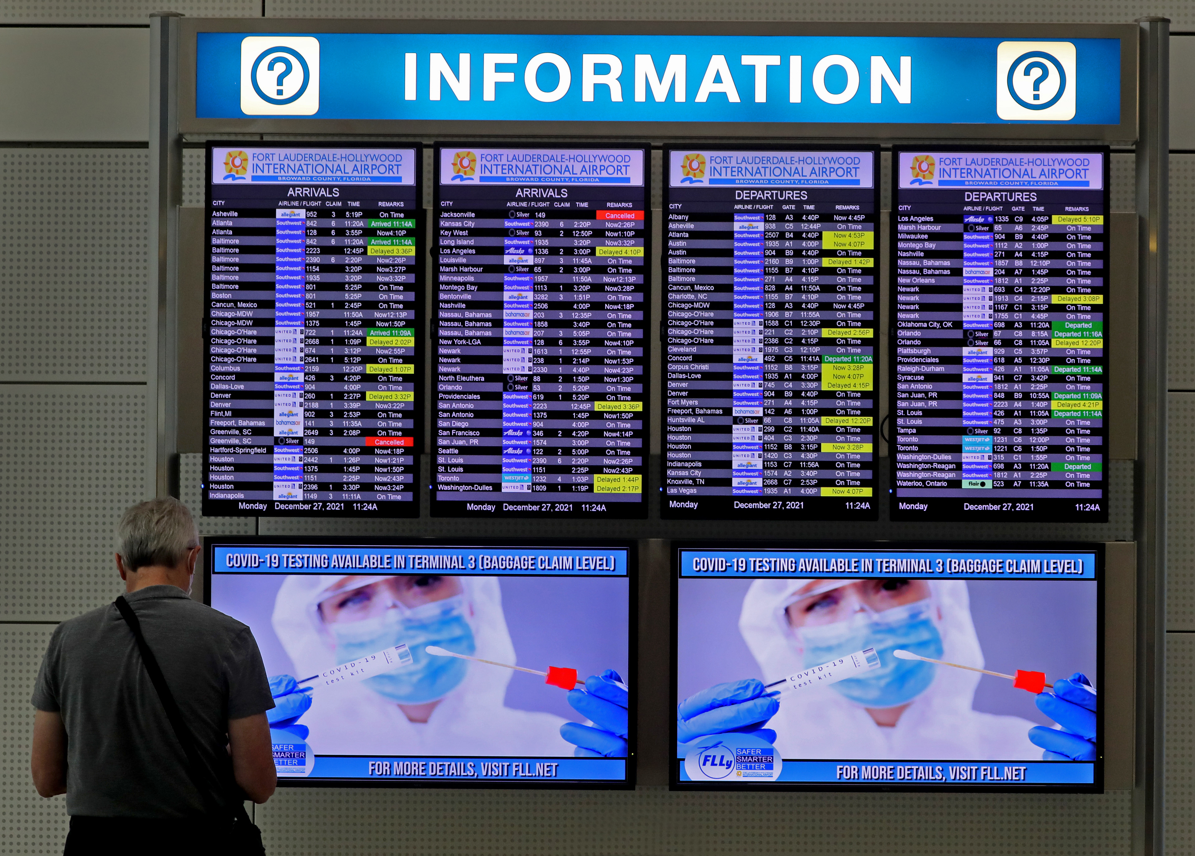 COVID-19 testing information is displayed on a departure and arrivals board at Fort Lauderdale/Hollywood International Airport in 2021.  Airlines canceled thousands of flights on Christmas Eve, including flights in and out of South Florida airports, as staff and crew got sick during the omicron surge.