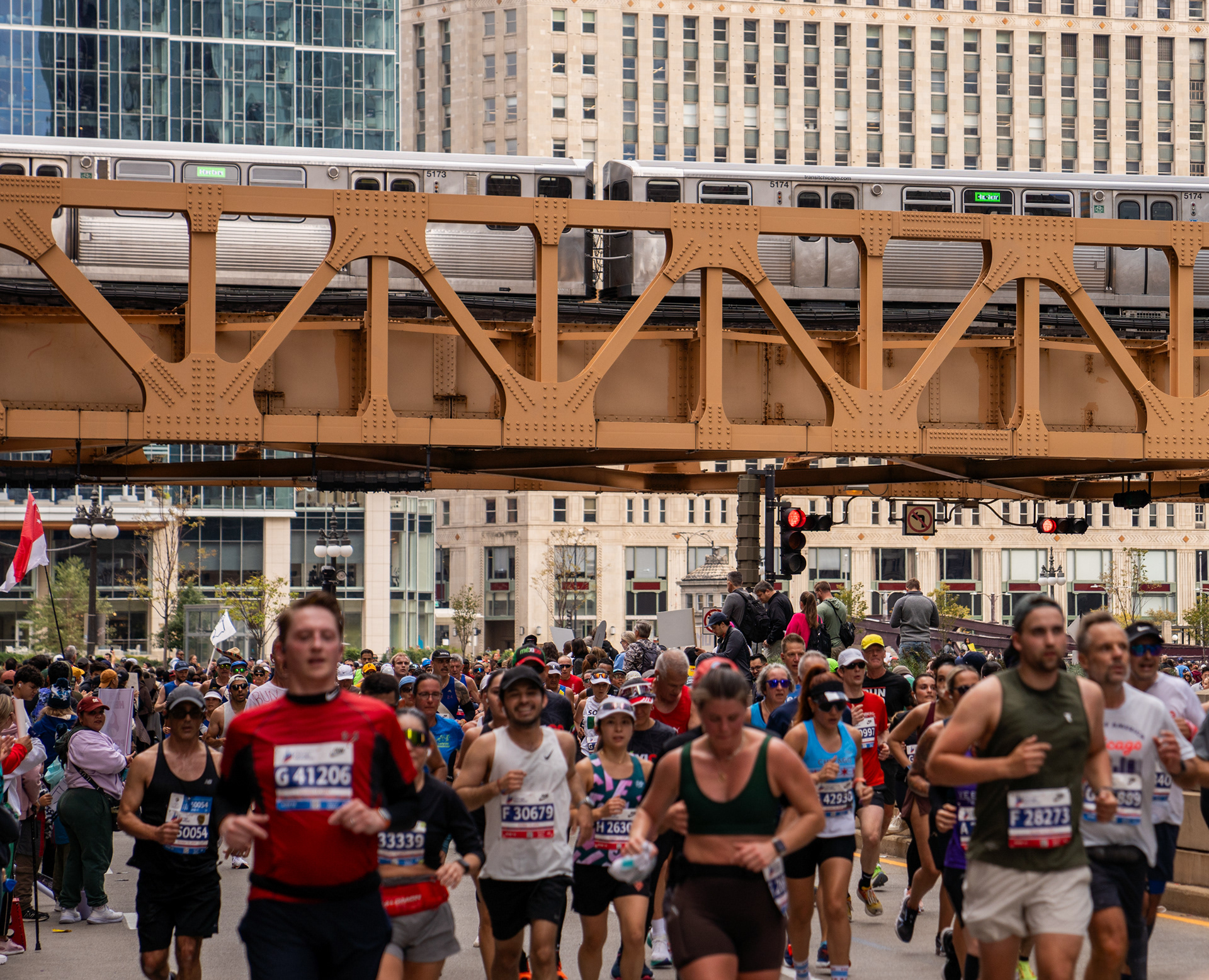 Runners pass the Lake Street bridge as the CTA Green Line passes above. Oct. 13, 2024.