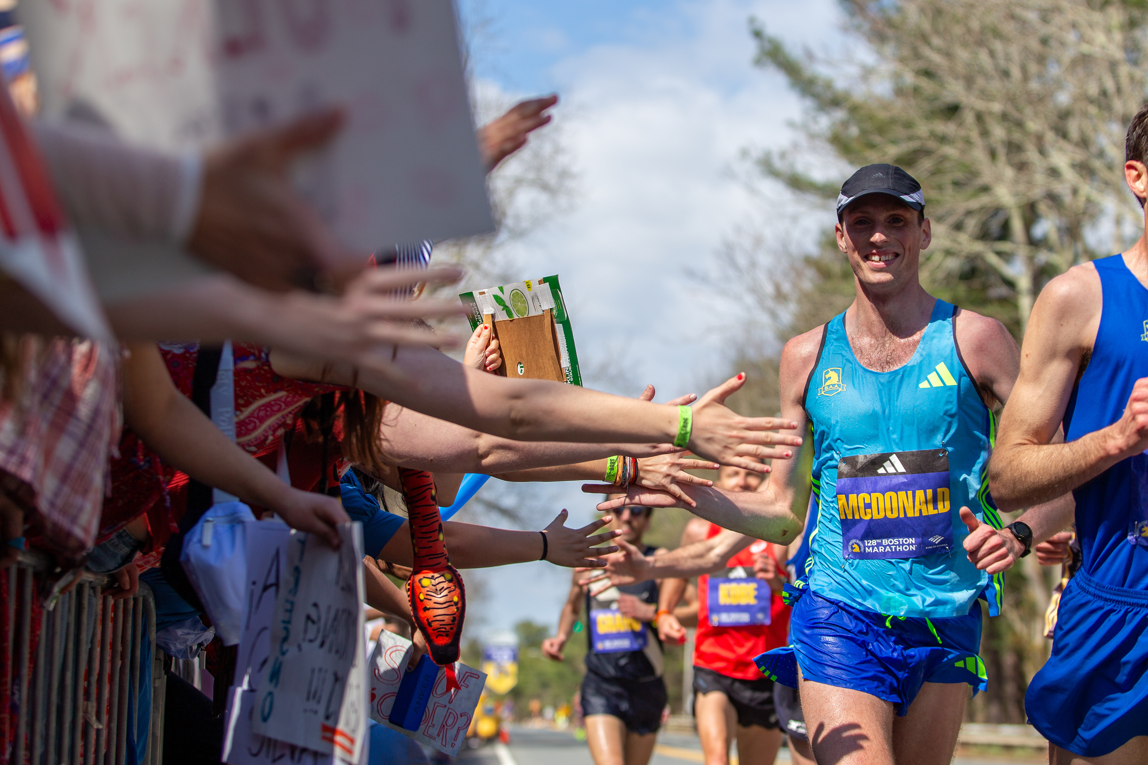 Wellesley, Mass. — American male elite runner Matthew McDonald, of Cambridge, high fives the crowd during the 128th running of the Boston Marathon, in front of Wellesley College, April 15, 2024.