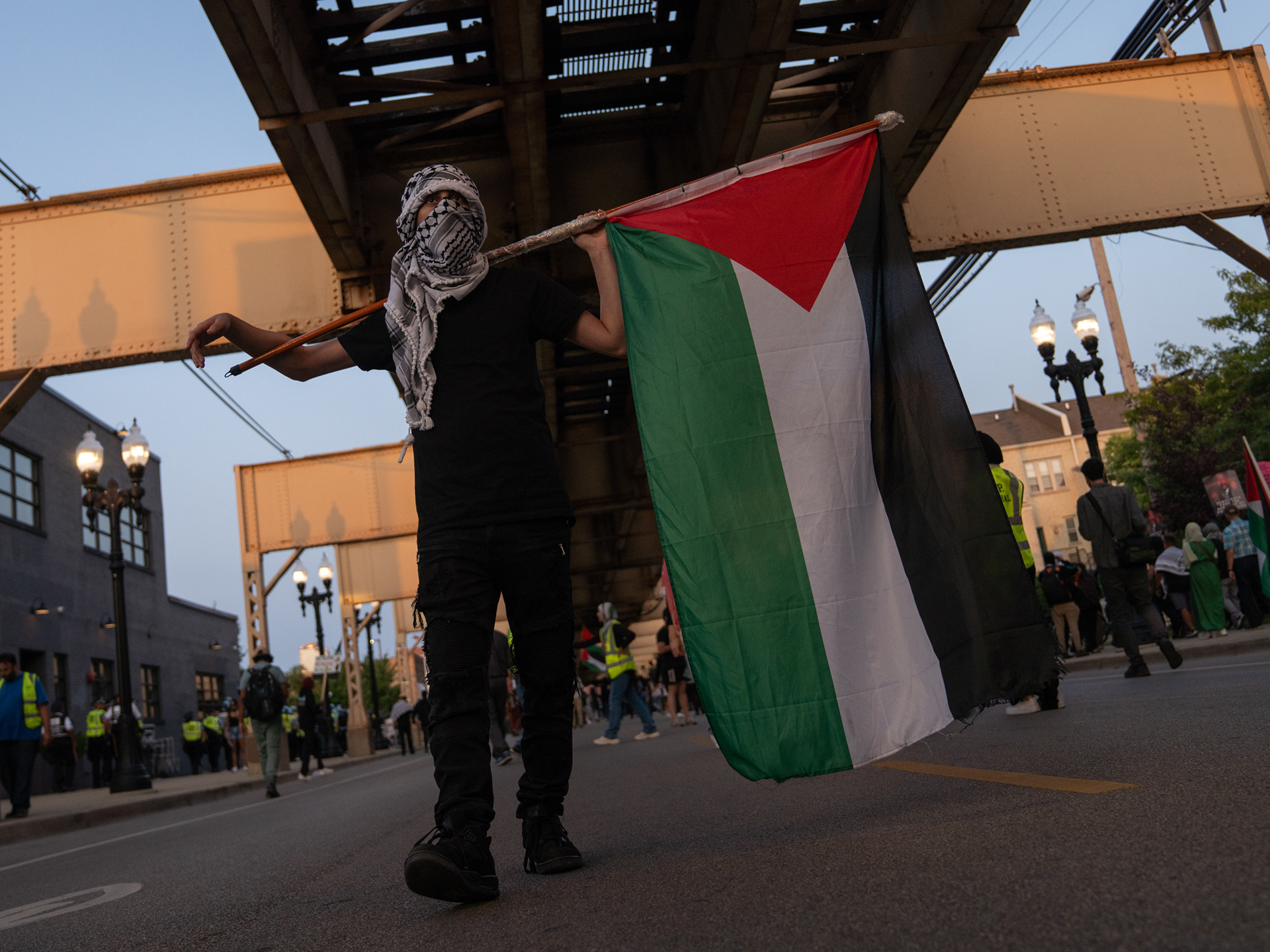 Chicago — A protester holding a Palestinian flag underneath the CTA tracks on W. Lake Street in Chicago, near the site of the DNC. Aug. 21, 2024.