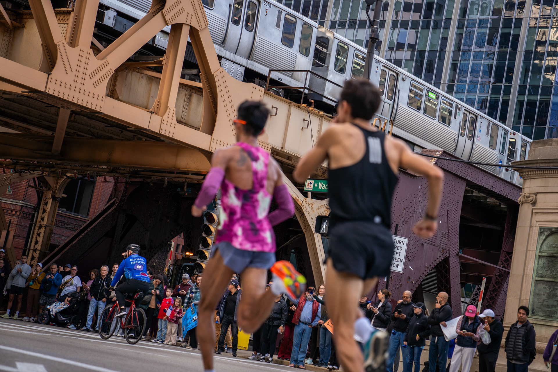 Two elite male runners prepare to pass under the CTA Green Line at Lake Street in the Chicago Marathon. Oct. 13, 2024.