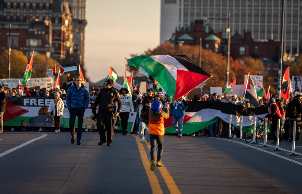 Boston — A young protester runs across the bridge holding the Palestinian flag as protesters walk towards Cambridge during a protest in November, 2023.
