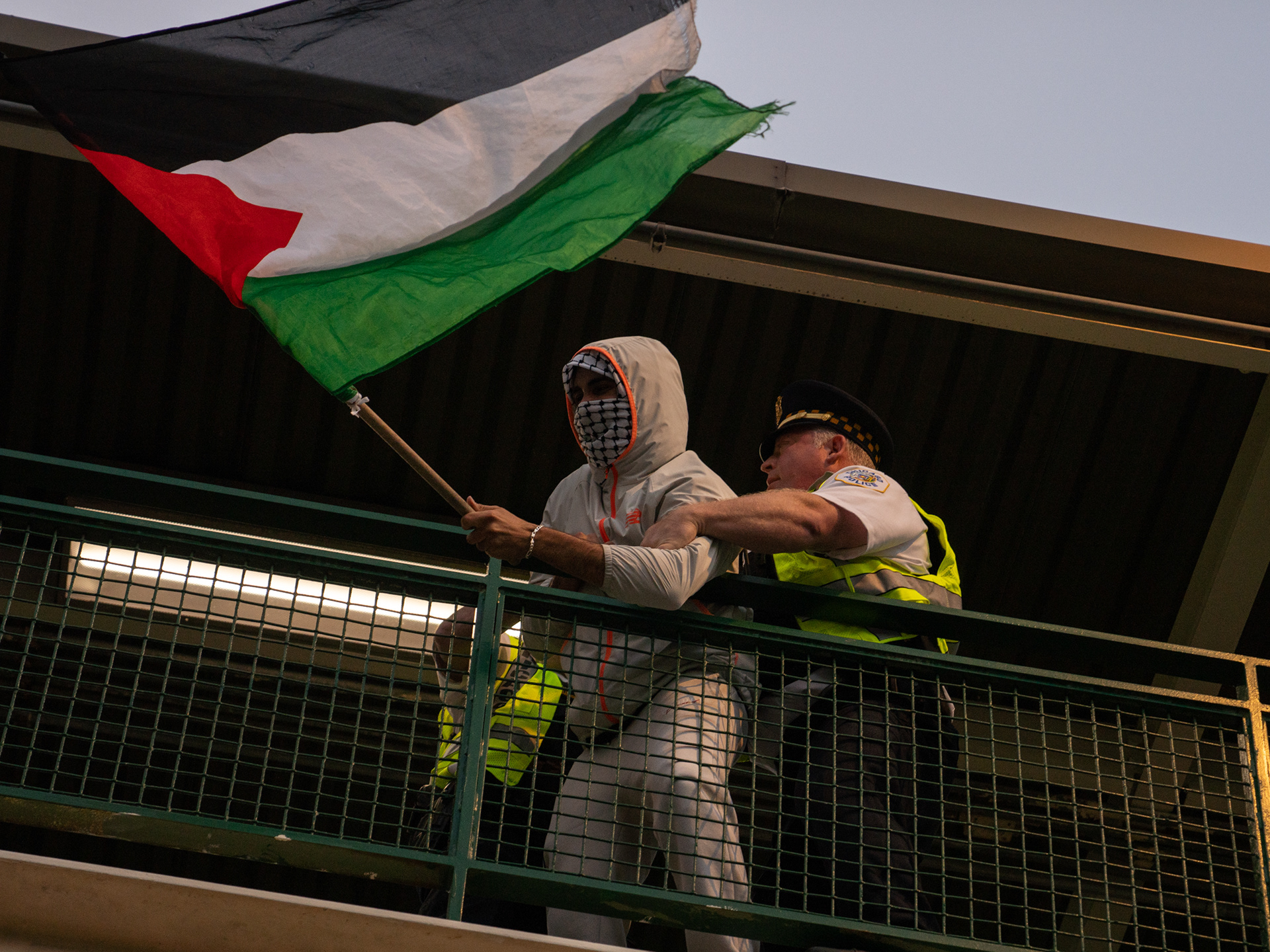 Chicago — A protester resisting police officers while waving a Palestinian flag from a CTA stop in Chicago. Aug. 21, 2024.