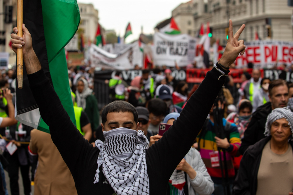 Washington — A protester holds a "peace" sign in one hand and a Palestinian flag in the other during a protest in Washington.