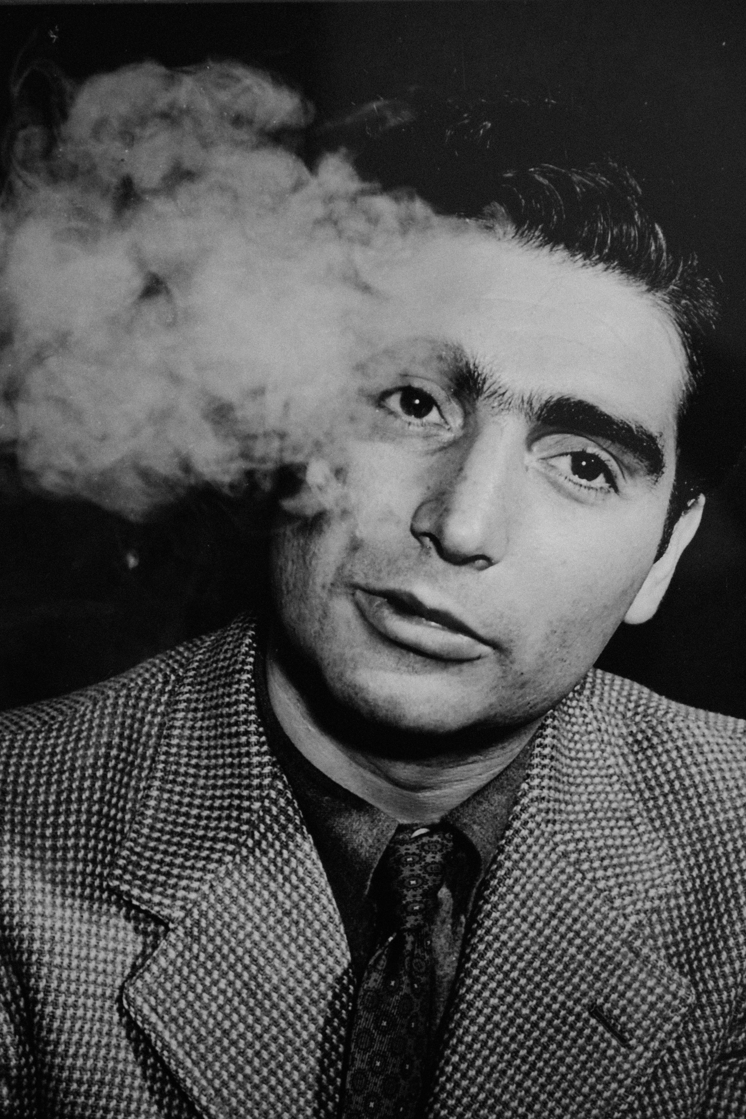 „Robert Capa raucht eine Zigarette – ikonisches Schwarzweißporträt des legendären Kriegsfotografen in einem stillen Moment. Ausdrucksstark, analog, zeitlos. Symbol für Fotografie, Mut und Geschichte. Idealbild für fujicolours.com – analoge Leidenschaft trifft visuelle Tiefe.“