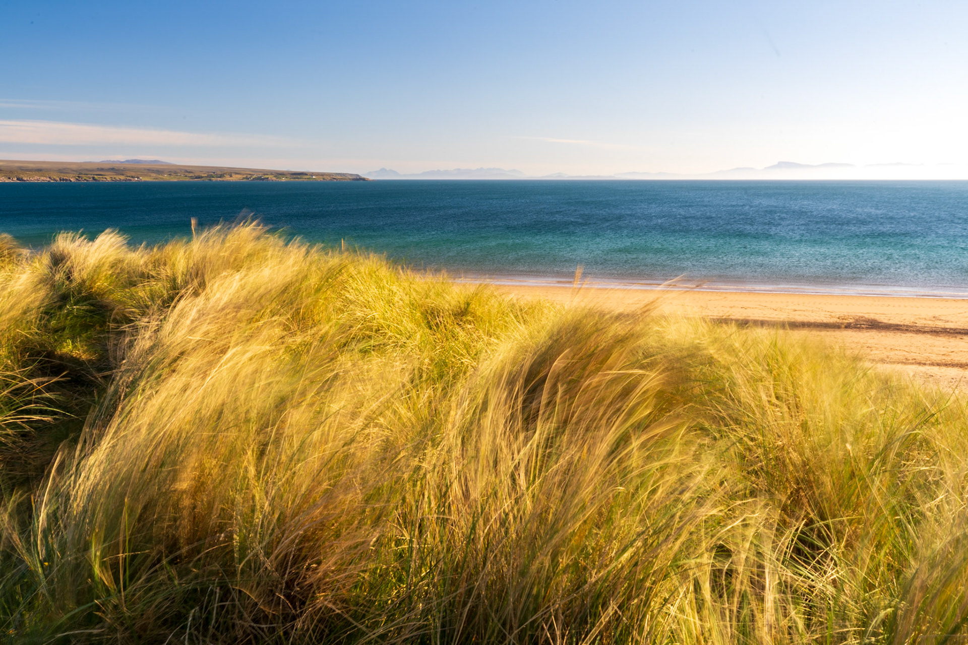 Dunes on Big Sands Beach look spectacular blowing in the wind, with the iconic Skye silouhette visible on the distant horizon.