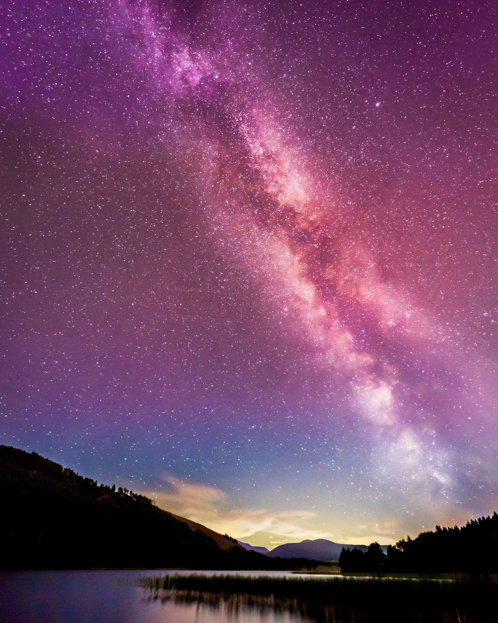 The bright aurora borealis with the southern milky way visible from the Cairngorms National Park (Loch Pityoulish), Scotland