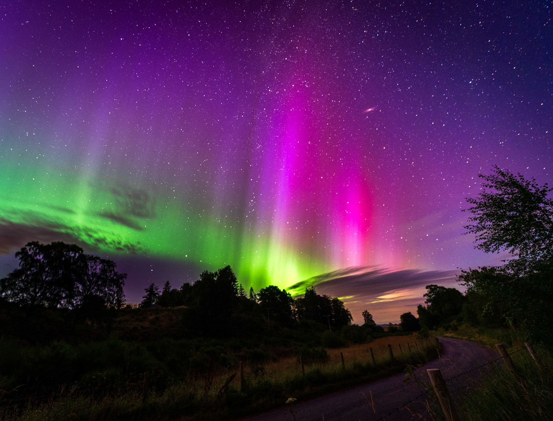 The bright aurora borealis with the Andromeda galacy visible from the Cairngorms National Park (Loch Pityoulish), Scotland