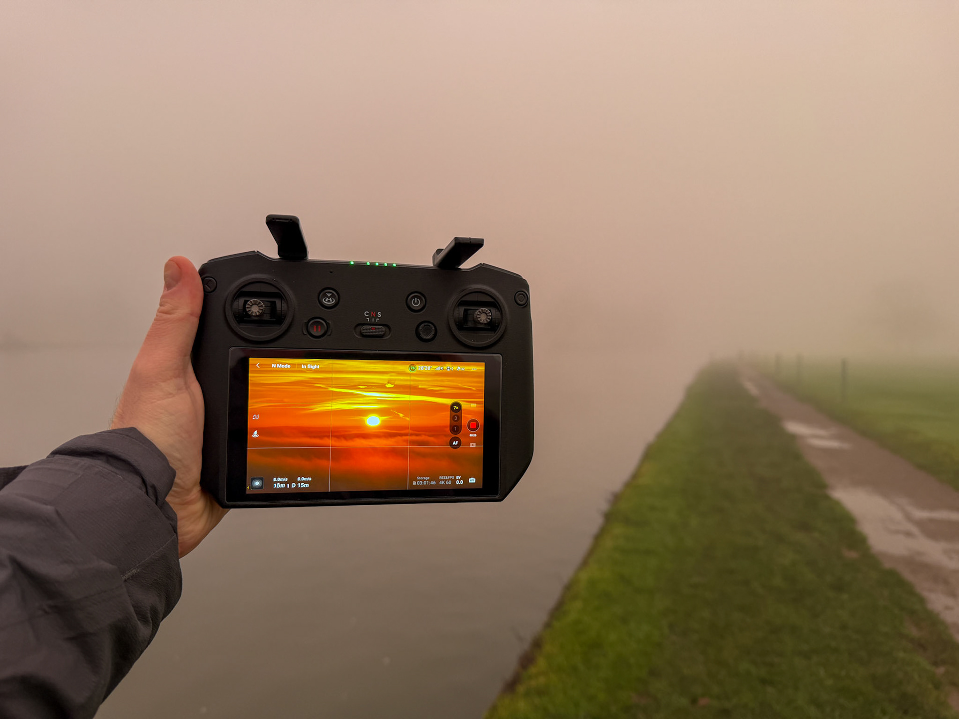 The DJI RC Pro Controller in my hand, showing a magical sunrise in the mist.