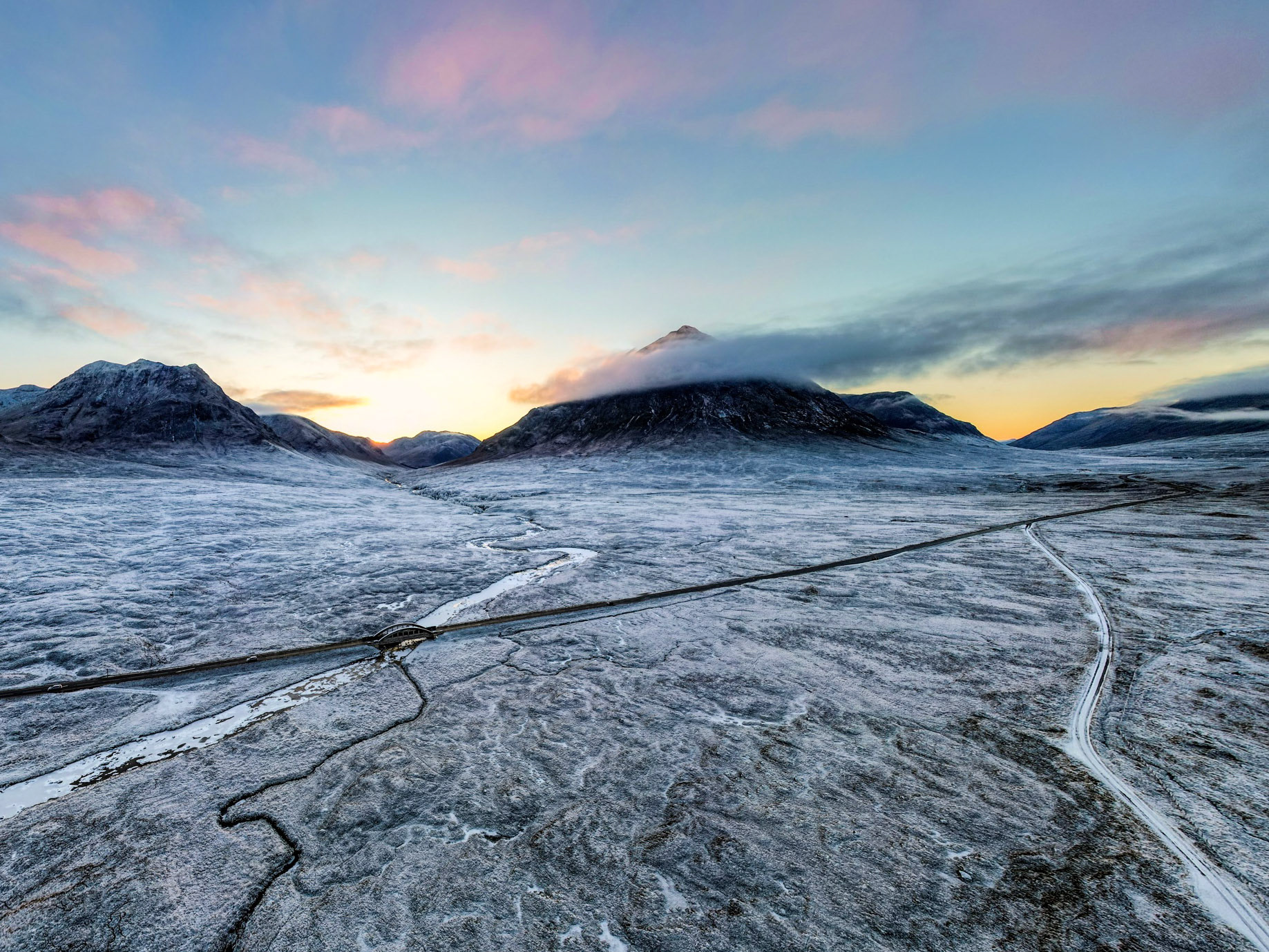A dramatic frost covered winter sunset Glencoe, showing the Buachaille shrouded in cloud, white ground and rivers