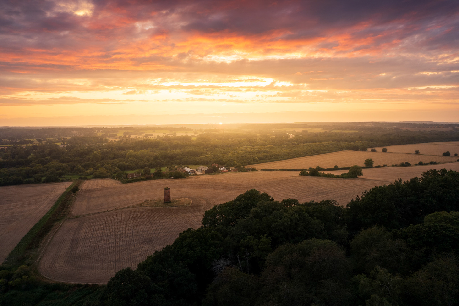 Wide view of a summer Wilders Folly in Berkshire, near Reading, UK. Taken from drone with a magical bright red sunset