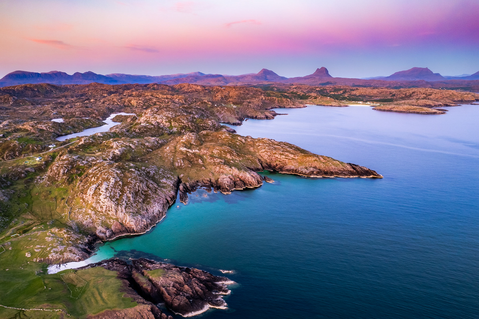 The gneiss rock, billions of years old, meets the turqoise waters of the Atlantic on the West coast of Scotland. Distant mountains sit on the horizon, looking absolutely majestic.
