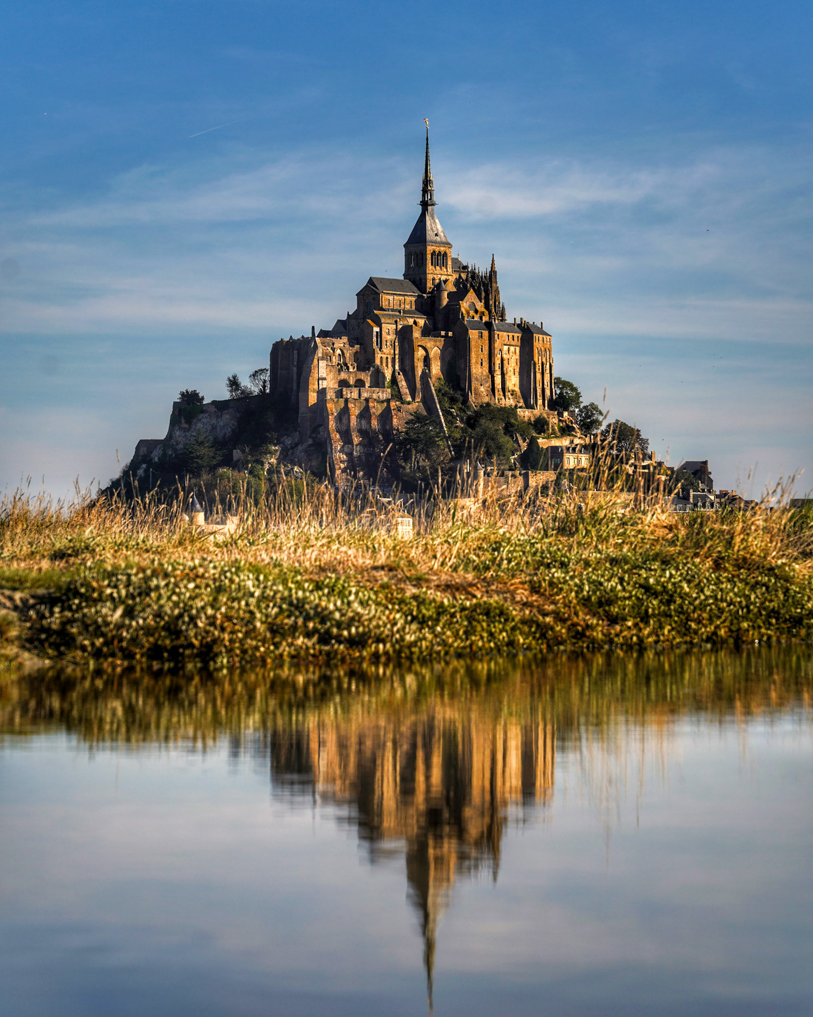 Mont Saint Michel reflecting off the river leading into the salt flats, Normandy, France