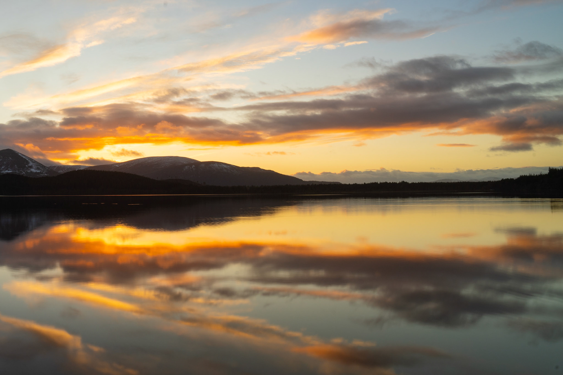 Loch Morlich during a beautiful winter sunset, Cairngorms, Scotland. Water reflects the beautiful colours.