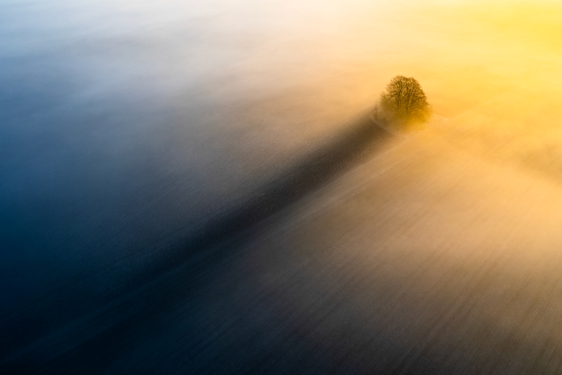 The Long Shadow - Oxfordshire, England - Early morning mist sits around this bronze age burial mound, where the sunrise caset a long shadow into the mist, creating a truly iconic and magical scene.