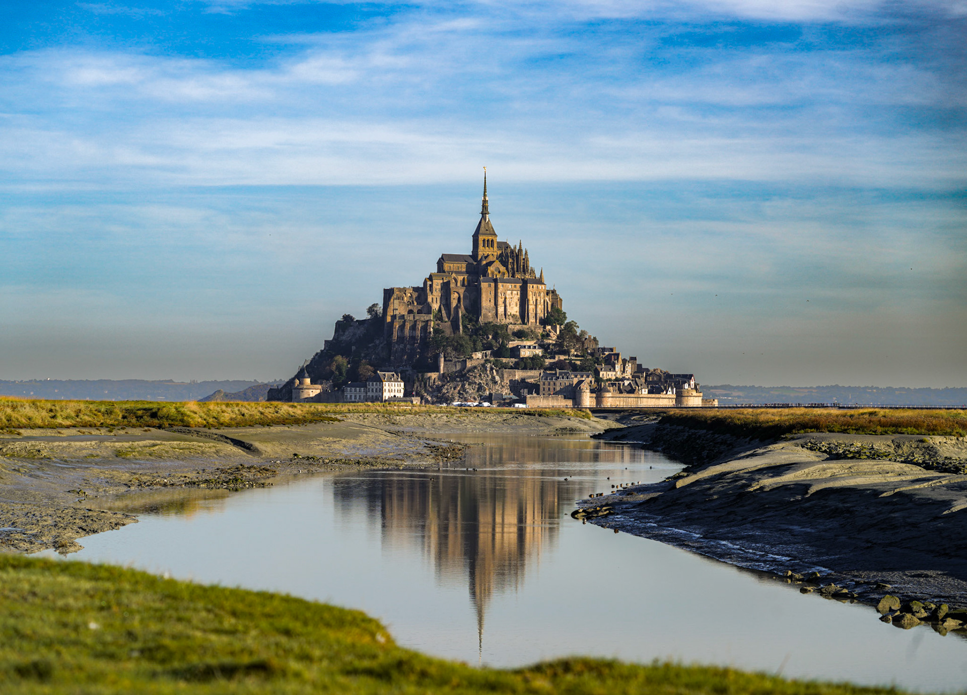 Mont Saint Michel reflecting off the river leading into the salt flats, Normandy, France